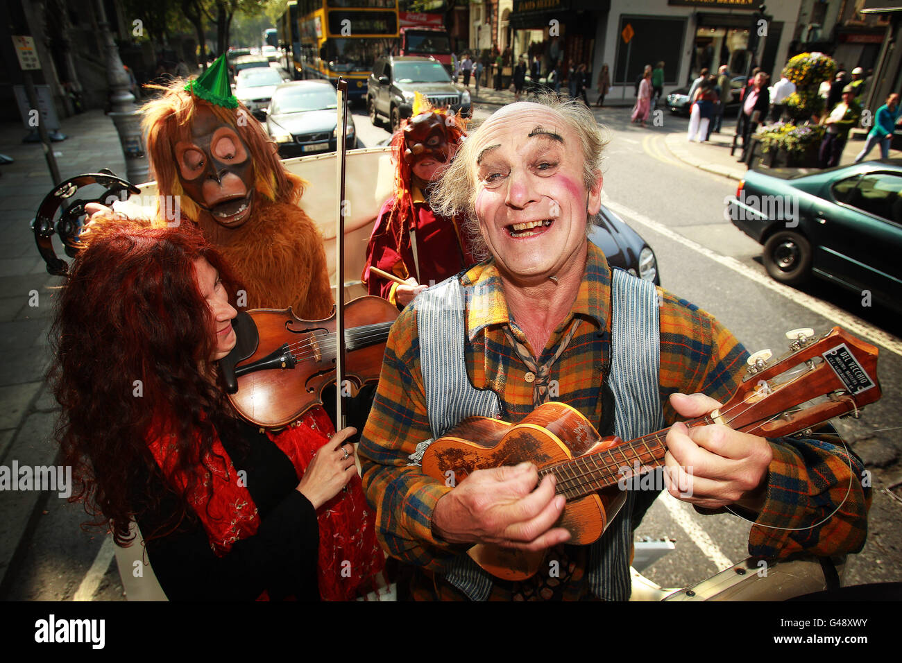 Paddy the Clown e i suoi artisti viaggiano per Dublino a cavallo e in carrozza nel caldo per celebrare la notizia che il teatro itinerante Footsbarn avrà un'ulteriore corsa di due settimane a causa della forte richiesta del pubblico. Foto Stock