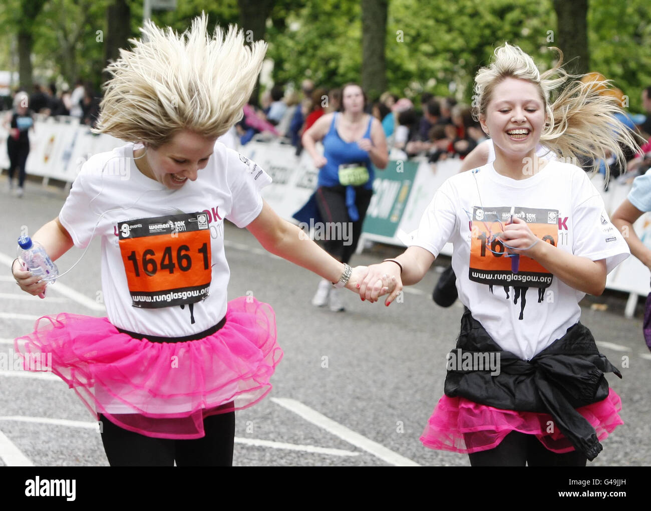 I runner festeggiano mentre attraversano il traguardo durante la 10k delle donne di gestione degli asset a Glasgow, Scozia. Foto Stock