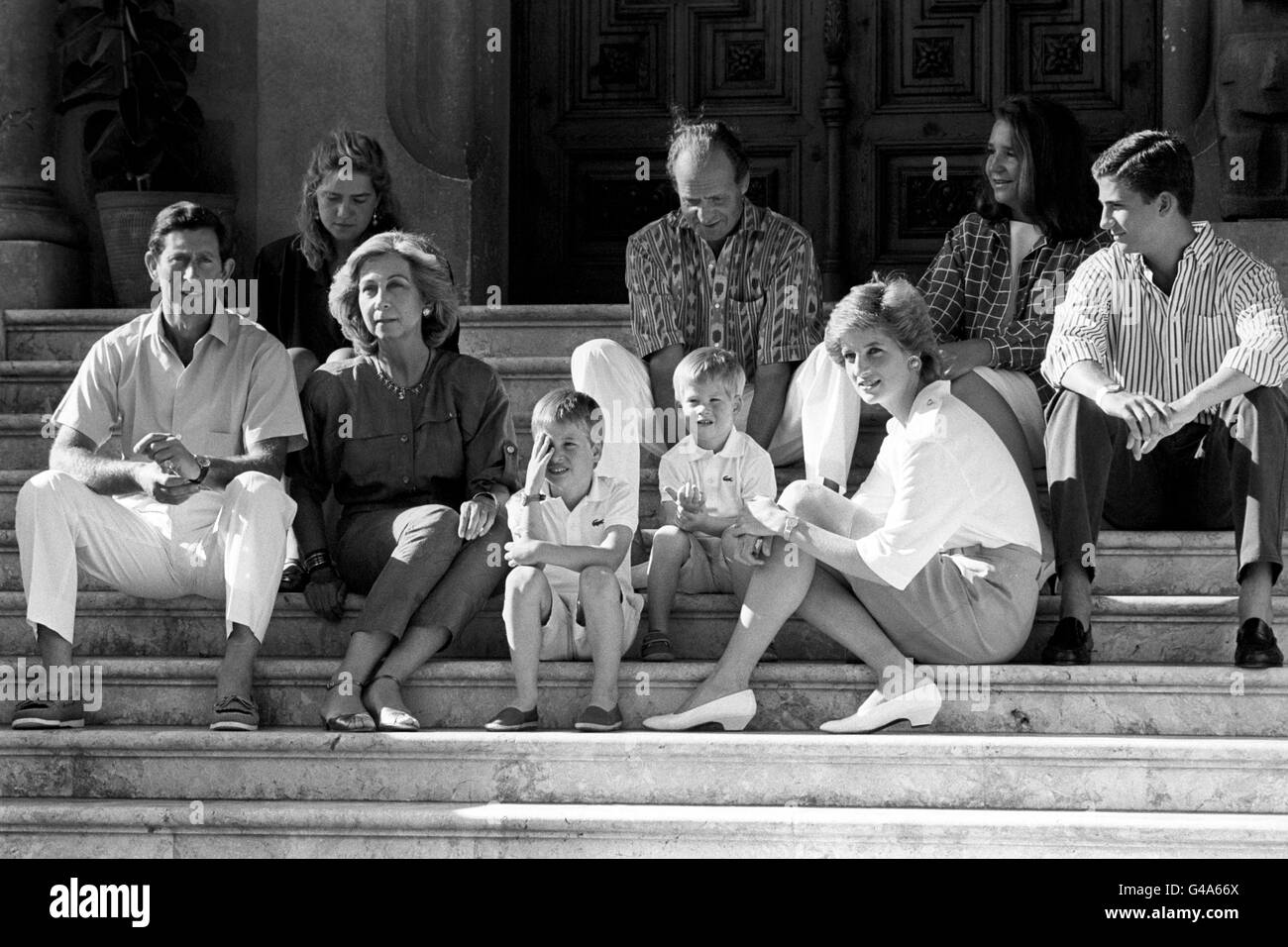 Il Principe Guglielmo di sei anni protegge gli occhi dal sole spagnolo mentre si pone per fotografie sui gradini del Palazzo Marivent con suo fratello il Principe Harry, la madre della Principessa del Galles (in basso a destra), e il padre il Principe del Galles (a sinistra). Con loro ci sono il re Juan Carlos (centro) e la regina Sofia di Spagna e i loro figli gli Infantes Cristina ed Elena e il principe Felipe. Foto Stock