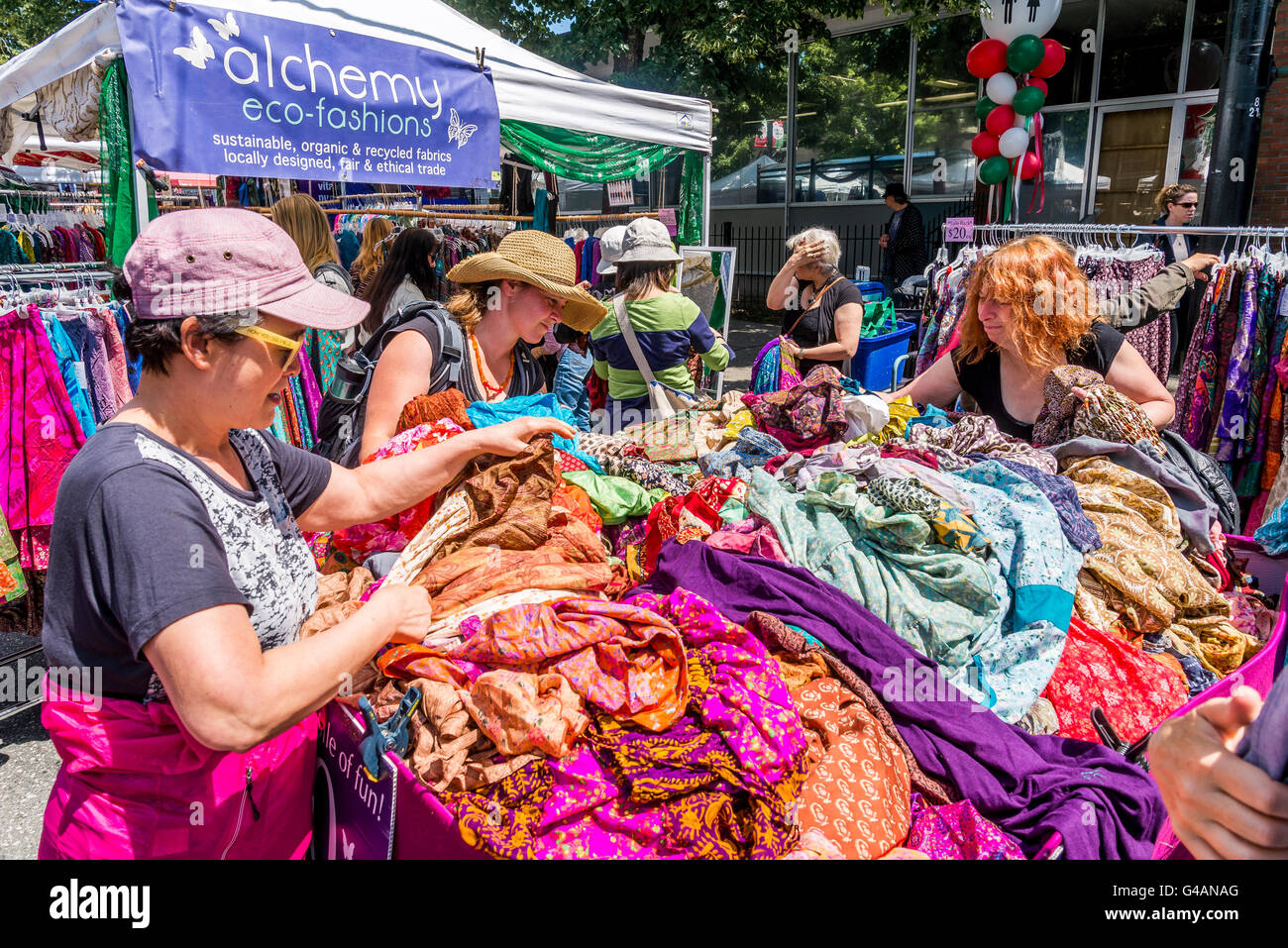 Donne scorazzare vestiti in stallo del mercato, Vancouver, British Columbia, Canada, Foto Stock