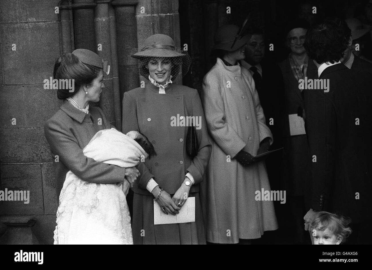 PA NEWS PHOTO 13/3/83 1983: LA PRINCIPESSA DEL GALLES GLANCIA LA SUA NUOVA DIVINITÀ-FIGLIA ALEXANDRA VICTORIA EDWINA DIANA NELLE BRACCIA DELLA MADRE LADY ROMSEY CON UN SORRISO ALLA CERIMONIA DI BATTESIMO SUI GRADINI DI ROMSEY ABBEY, HAMPSHIRE. Foto Stock