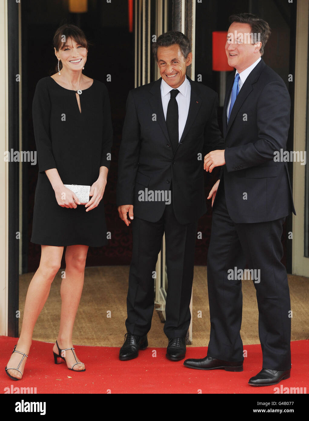 Il presidente francese Nicolas Sarkozy e sua moglie Carla Bruni salutano il primo ministro britannico David Cameron (destra) e gli altri leader del G8, che si uniranno a loro per cena alla fine della prima giornata del G8, a Deaville, in Francia. Foto Stock