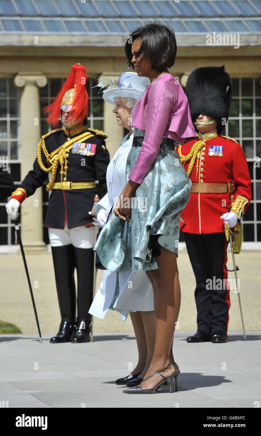 La gonna della First Lady Michelle Obama (a destra) è catturata nel vento mentre si trova con la Regina Elisabetta II nel giardino di Buckingham Palace a Londra, il primo giorno della visita di stato di tre giorni del presidente Obama nel Regno Unito. Foto Stock