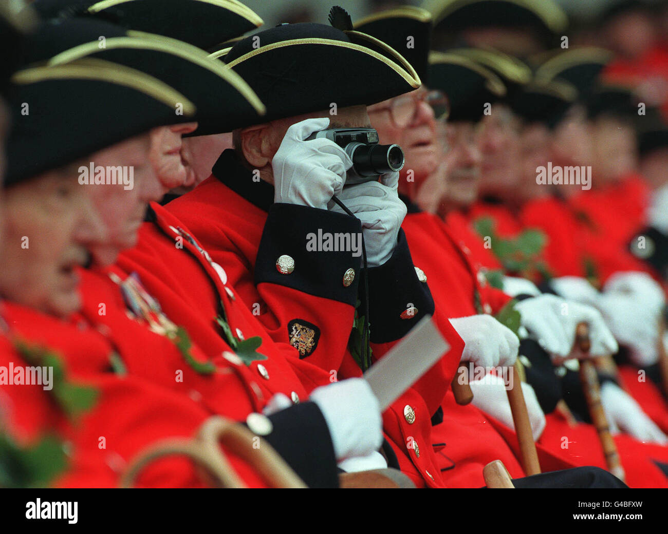 Un seduto Chelsea pensionato prende una foto dei suoi colleghi sul parade presso la festa del Fondatore celebrazione per il Royal Hospital Chelsea a Londra, oggi (giovedì). L'ospedale è stata fondata nel 1681 come ospizio per i vecchi soldati da re Carlo II e foglie di quercia sono indossati dai pensionati in memoria della sua via di fuga dopo la battaglia di Worcester nel 1651 quando ha preso rifugio dai suoi inseguitori in una quercia. AP WPA ROTA da Louisa Buller. Foto Stock