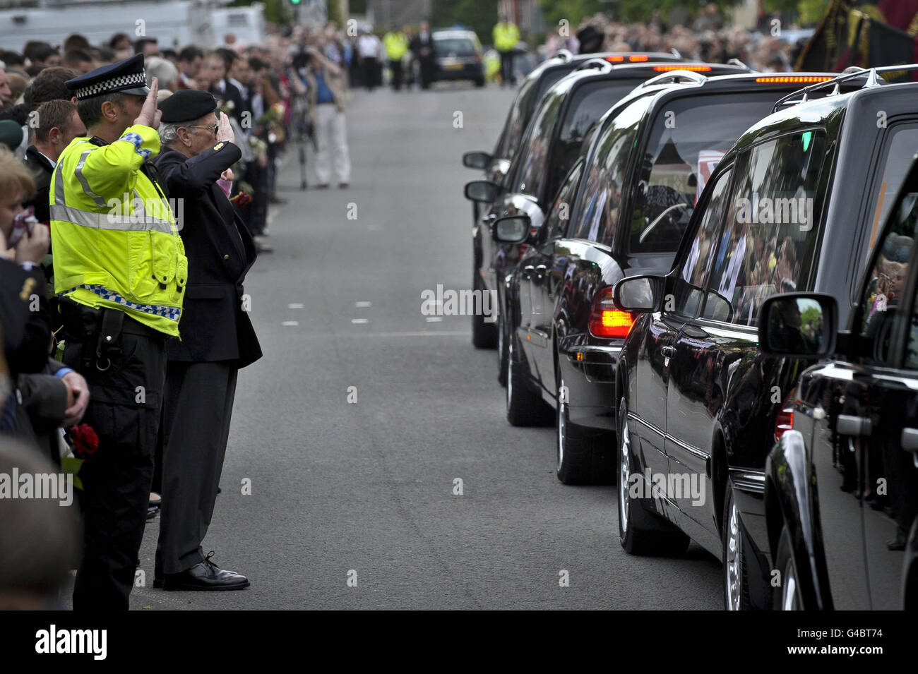 La polizia e i membri della Legione Britannica reale salutano tre audizioni, ciascuna contenente una bandiera dell'Unione drappeggiato di barbe con i corpi del caporale Michael Pike, 4° Battaglione del reggimento reale di Scozia, del caporale Lance Martin Gill, del 42 Commando Royal Marines e del Rifleman Martin Lamb, 1° Battaglione i fucili mentre si fermano su High Street a Wootton Bassett, Wiltshire dopo essere stati rimpatriati a RAF Lyneham. Foto Stock