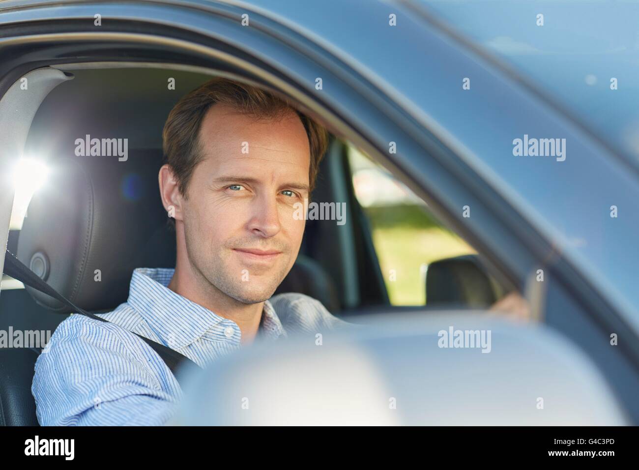 Modello rilasciato. Metà uomo adulto in auto, sorridente. Foto Stock