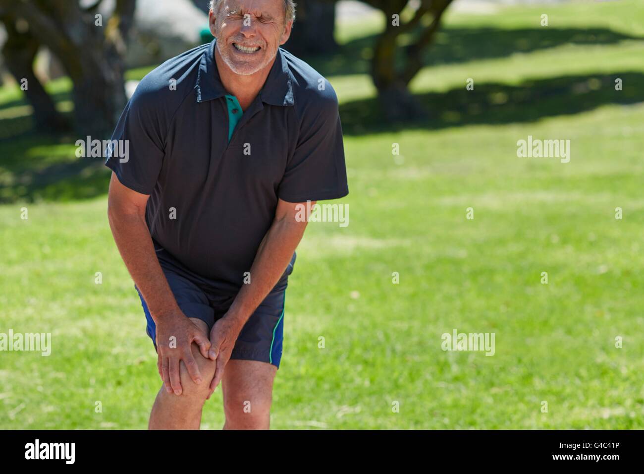 Modello rilasciato. Senior uomo con il suo ginocchio nel dolore. Foto Stock