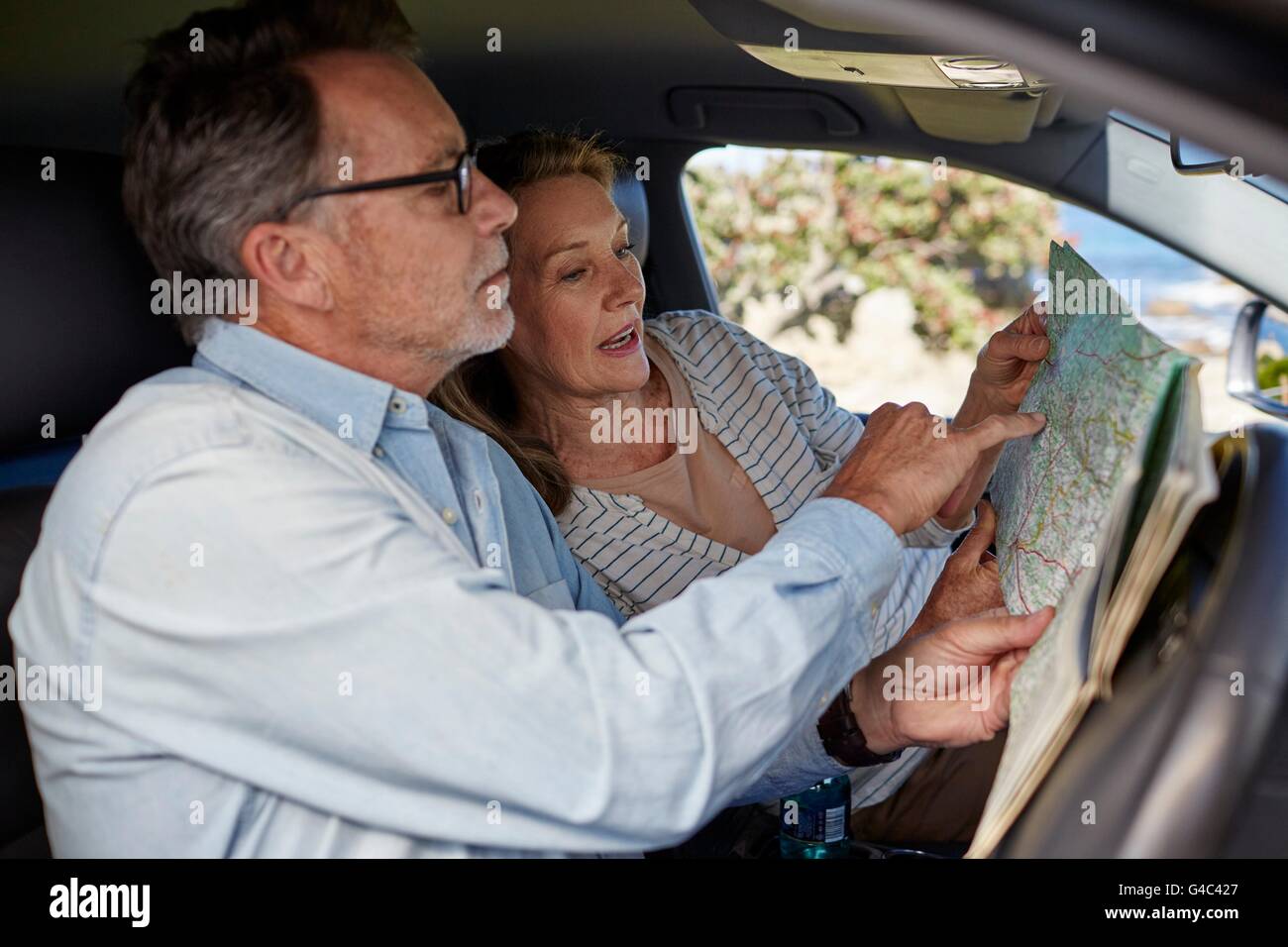 Modello rilasciato. Coppia senior in auto la lettura di una mappa. Foto Stock