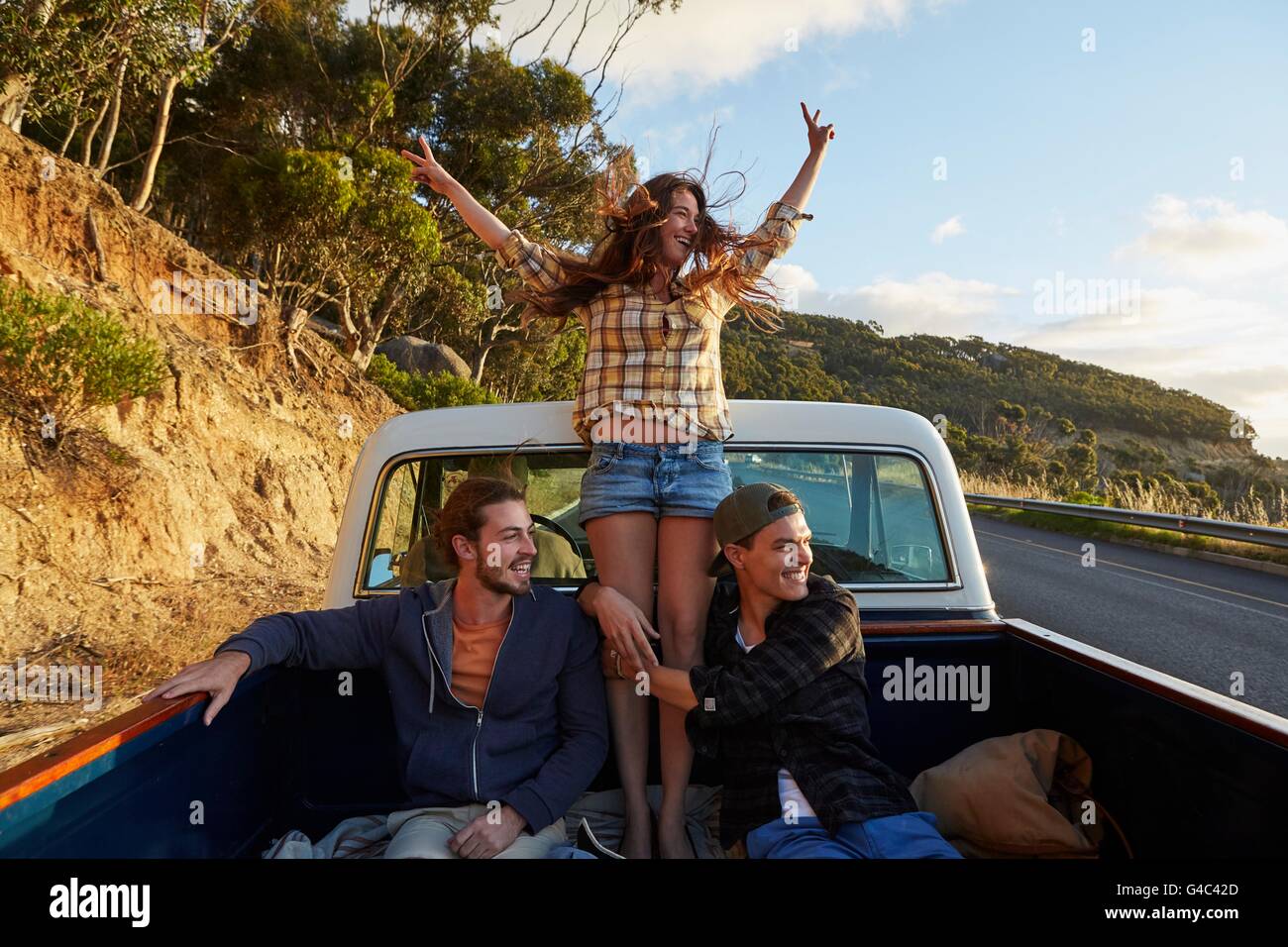 Modello rilasciato. Giovane donna in pick up truck con le braccia sollevate. Foto Stock