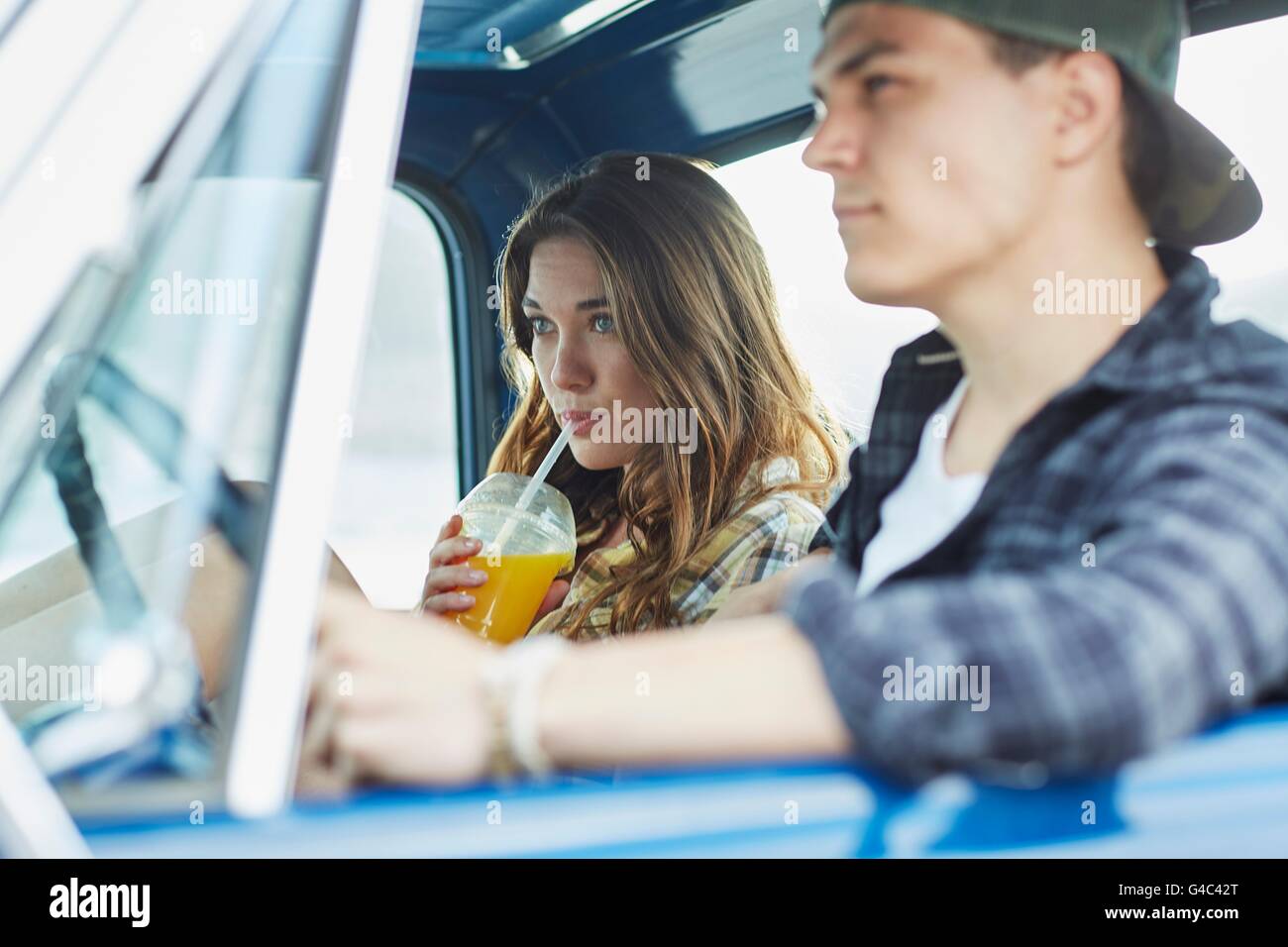 Modello rilasciato. Coppia giovane in un auto, donna di bere succo di frutta. Foto Stock