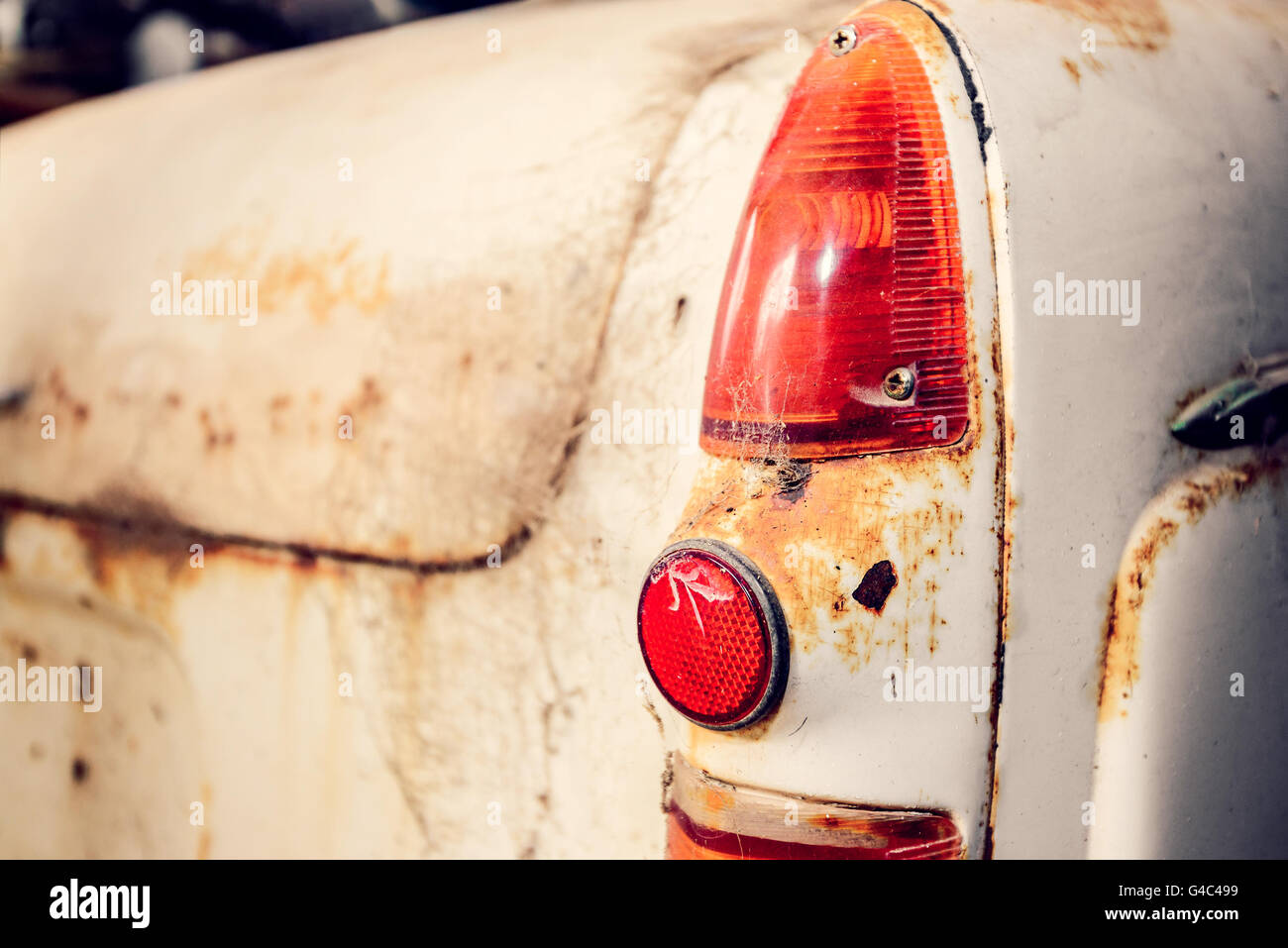 Vista posteriore della vecchia auto abbandonate con incrinato luce di coda coperti con il web. Color-tonificante effetto applicato. Foto Stock