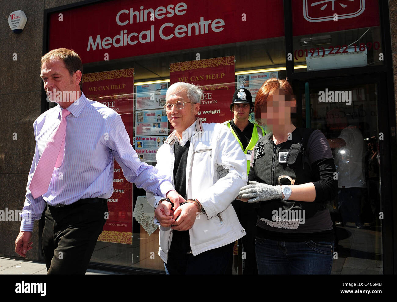 FACCIA OSCURATA DA PICTURE DESK SU RICHIESTA DELL'AGENZIA di FRONTIERA britannica UN uomo è portato via dal Centro medico cinese a Newcastle dalla polizia e funzionari dell'Agenzia di frontiera britannica, dove è stata arrestata per sospetto di traffico di persone nei locali. Foto Stock