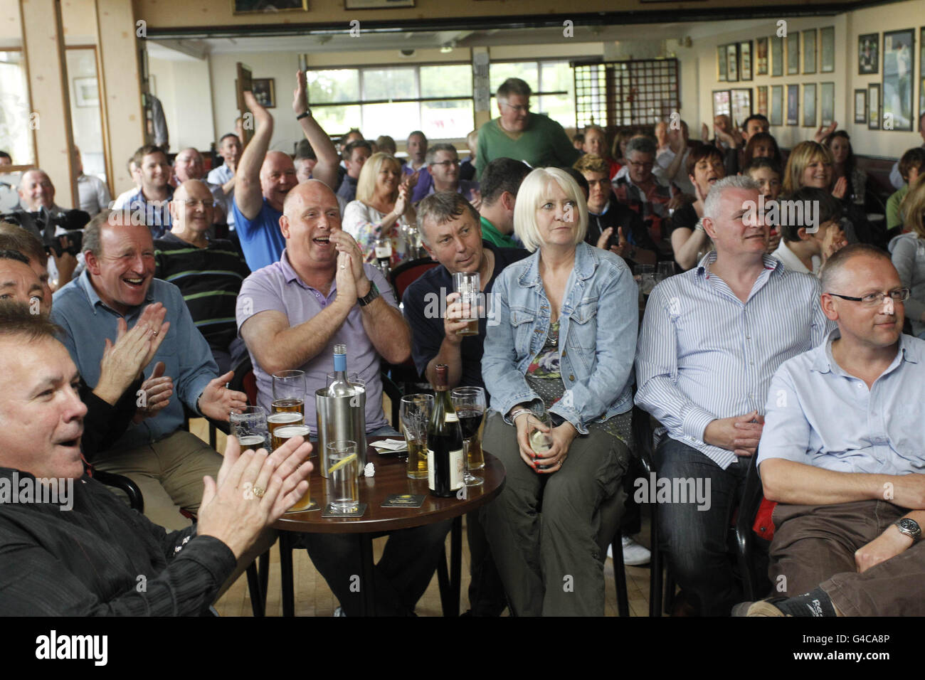 Amici del golfista Rory McIlroy all'Holywood Golf Club in Co. Giù Irlanda del Nord, applaudire come ha esteso la sua guida da otto a 10 come l'Open degli Stati Uniti è rimasto uno spettacolo di un uomo al Congresso oggi. Foto Stock