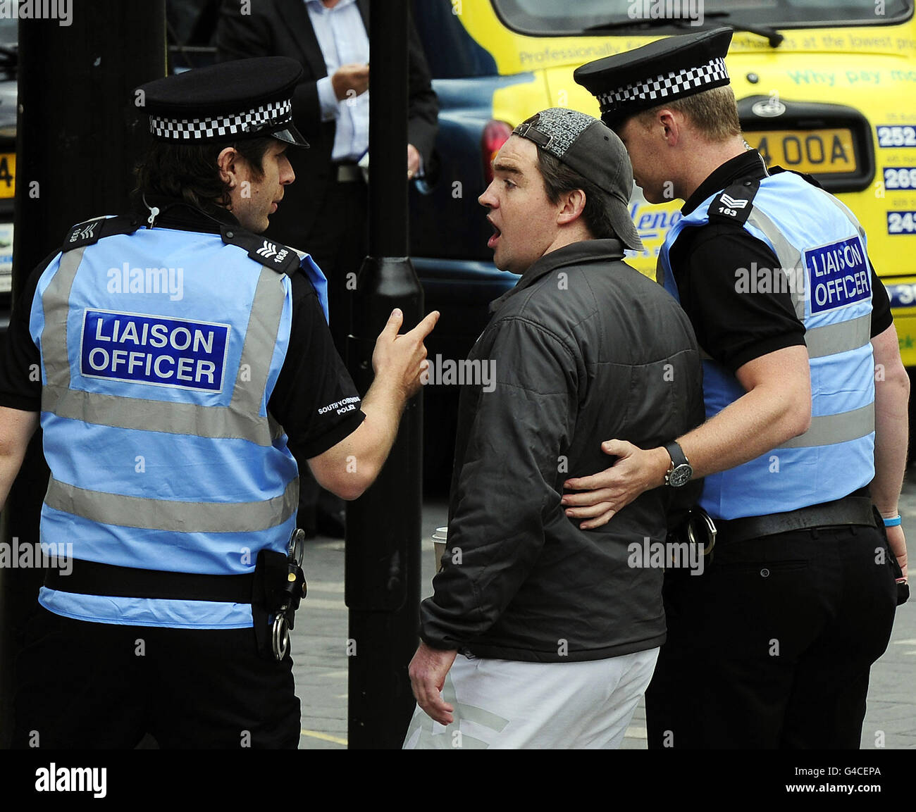 Un membro del pubblico guidato via dalla polizia dopo aver espresso il suo disaccordo con i manifestanti dei tagli del settore pubblico a City Hall, Sheffield. Foto Stock