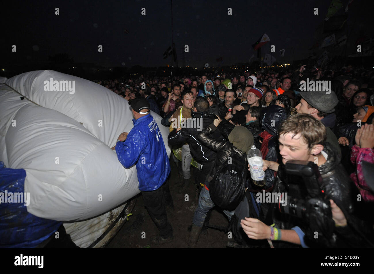 Il personale addetto alla sicurezza e i membri del gruppo d'azione diretta Art Uncut, si esibiscono su un pallone da 20 piedi, blasonato con il messaggio "U Pay Your Tax 2", mentre la rock band U2 si esibisce sul palco della Pyramid al festival musicale di Glastonbury presso la Worthy Farm, Pilton. Foto Stock