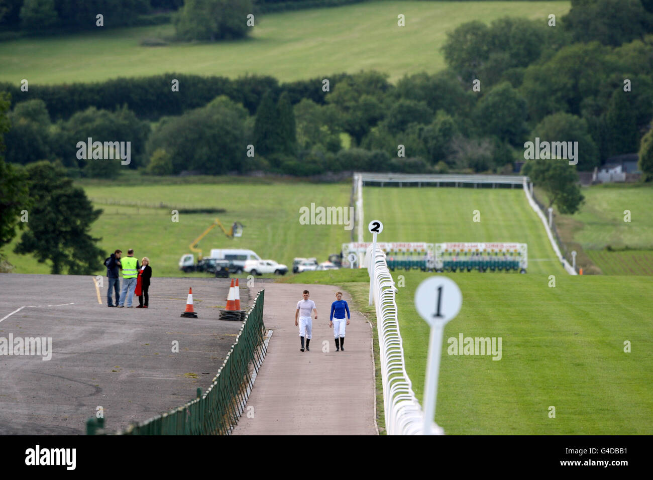 Corse di cavalli - Summer Race Night - Ippodromo di Chepstow. Due jockey camminano accanto ad un campo vuoto all'ippodromo di Chepstow Foto Stock