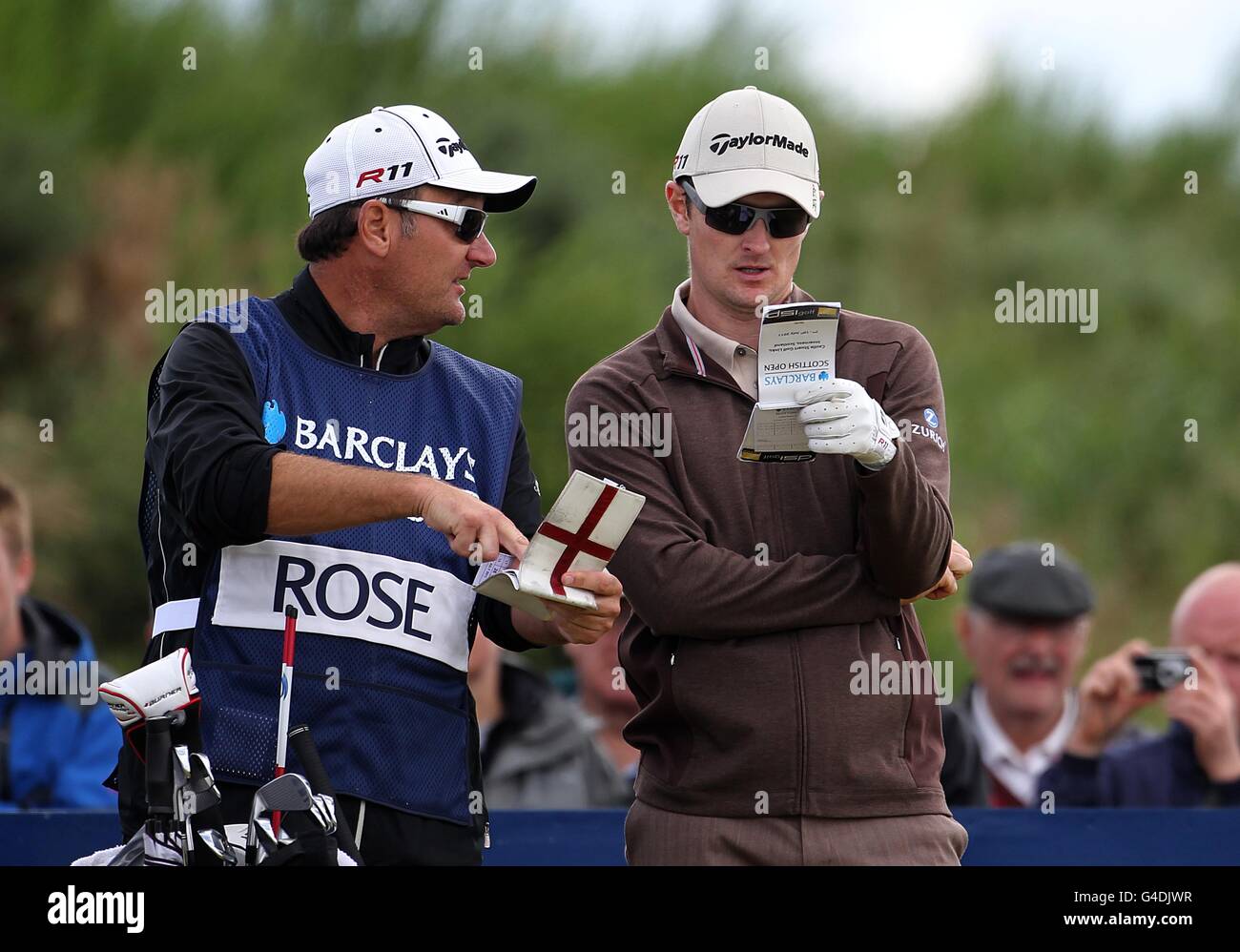 Justin Rose dell'Inghilterra e il suo cadie controllano lo yardage durante il giorno uno del Barclays Scottish Open, a Castle Stuart Golf Links, Inverness. Foto Stock