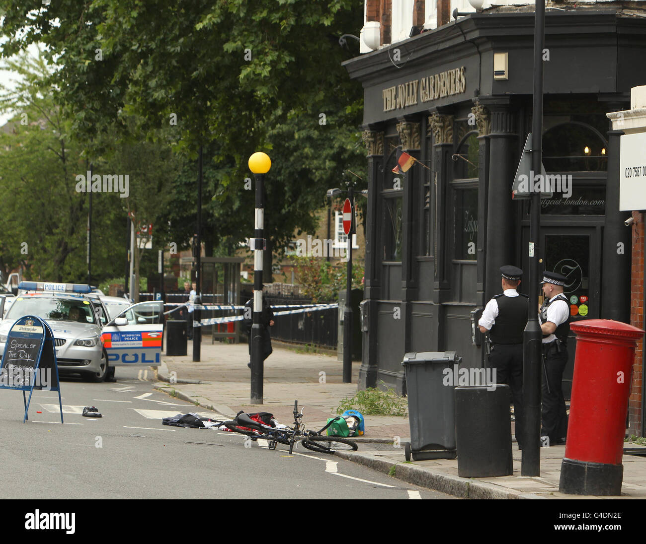 Gli ufficiali di polizia sono visti con una bicicletta sul posto di un tiro su Black Prince Lane a Kennington, nel sud di Londra. Foto Stock