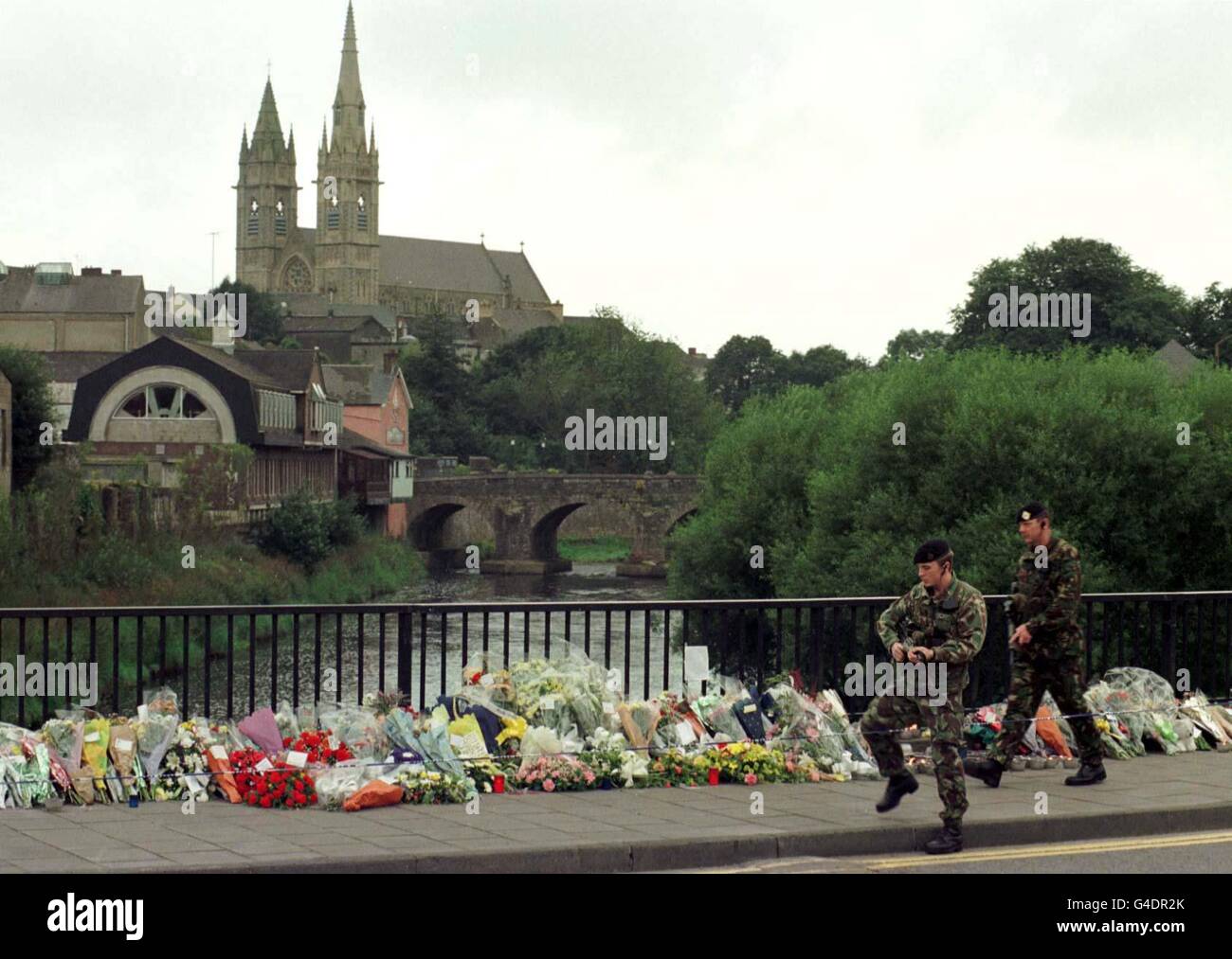 Una pattuglia dell'esercito attraversa oggi il ponte Strule a Omagh (mercoledì) passando decine di tributi floreali e messaggi di simpatia a seguito dei bombardamenti della città lo scorso sabato. Il ponte sul fiume Strule è ora il punto focale per la posa di fiori e messaggi. Foto John Giles/PA. Scopri LA storia di ULSTER Blast. Foto Stock