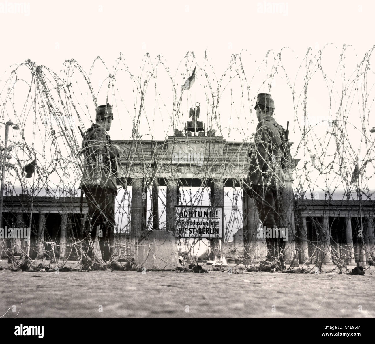 Le guardie di frontiera della Germania Est osservano dietro il filo a fisarmonica alla porta di Brandeburgo poco dopo la costruzione del muro di Berlino, 1961Costruzioni del muro di Berlino agosto 1961 le prime barriere alla porta di Brandeburgo . Topografia del terrore museo storico sul sito dell' ex sede della Gestapo a Berlino Germania ( Topographie of Terror museo storico sul sito dell' ex sede della Gestapo a Berlino Germania ) Foto Stock