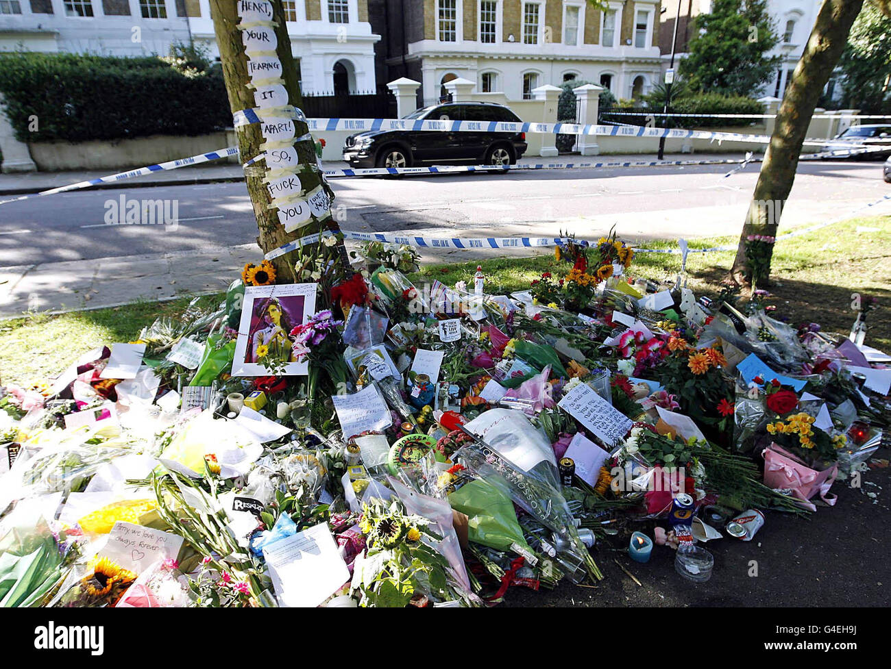 I REDATTORI NOTANO IL CONTENUTO. Fiori, tributi e testi di canzoni sono lasciati fuori dalla casa nord di Londra di Amy Winehouse dove è stata trovata morta il sabato. Foto Stock