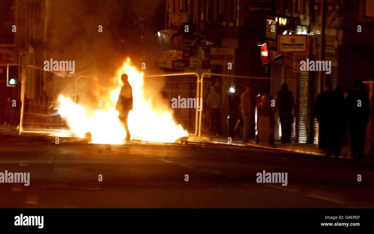 Un tiratore cammina attraverso una barricata ardente su Smithdown Road a Liverpool, mentre circa 200 giovani che lanciano missili si sono riuniti nella zona di Toxteh a Liverpool causando disordine e danni. Foto Stock