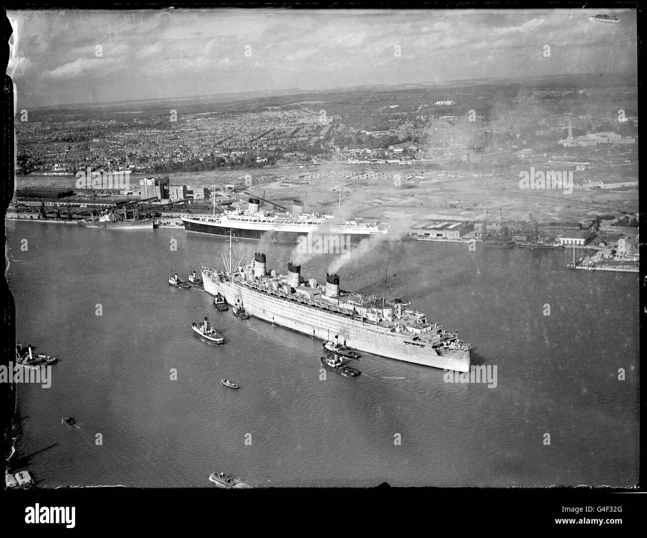 La Cunard White Star "Queen Mary", diciotto ore in ritardo da Halifax, Nuova Scozia, Canada, è arrivata a Southampton in tempo per stabilire un nuovo record di 3 giorni, 15 ore, 48 minuti per l'attraversamento. È stato l'ultimo viaggio della nave come trasporto di guerra, e ora subirà la riconversione a un aereo di linea passeggeri di lusso. Sullo sfondo è la sua nuova nave sorella, la 'Regina Elisabetta', in attesa di fare il suo viaggio inaugurale. Foto Stock