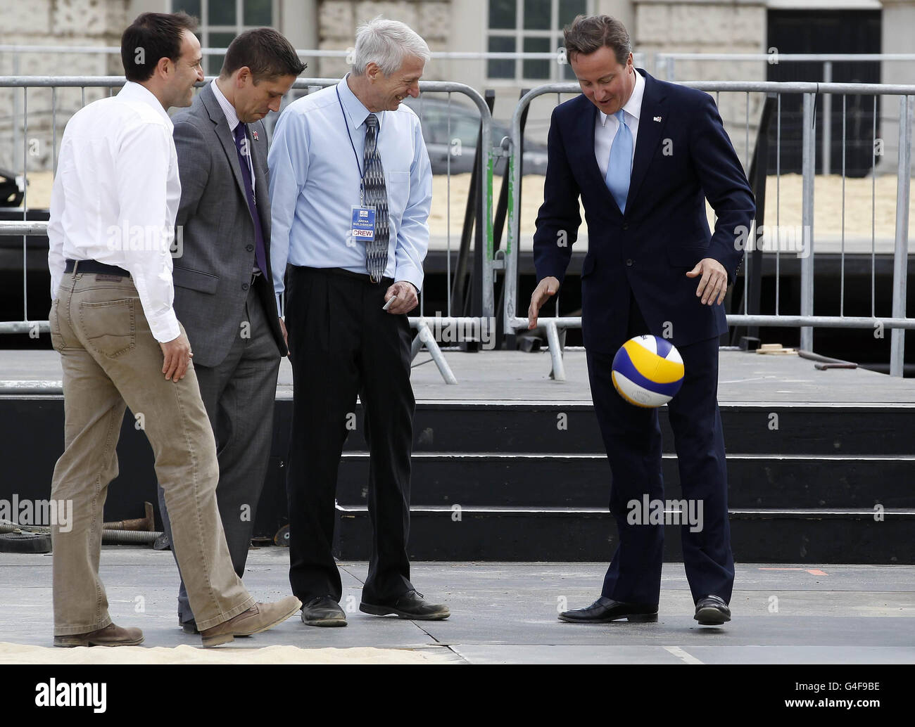 Il primo ministro David Cameron gioca con una pallavolo nel campo da Beach volley per i Giochi Olimpici del 2012, alla Horse Guards Parade di Londra. Foto Stock