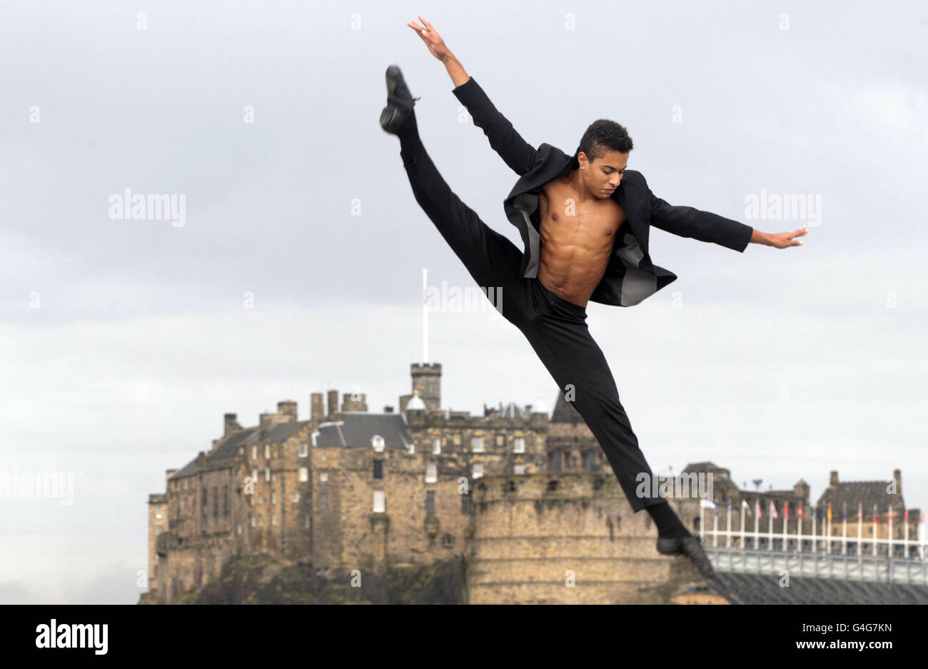 L'artista del balletto rock Lee Gumbs esegue salti e mosse di danza su una terrazza sul tetto di fronte al Castello di Edimburgo, prima del suo spettacolo di festival utilizzando il balletto e il teatro musicale presso l'Assembly Hall, che si svolge fino al 28 agosto. Foto Stock