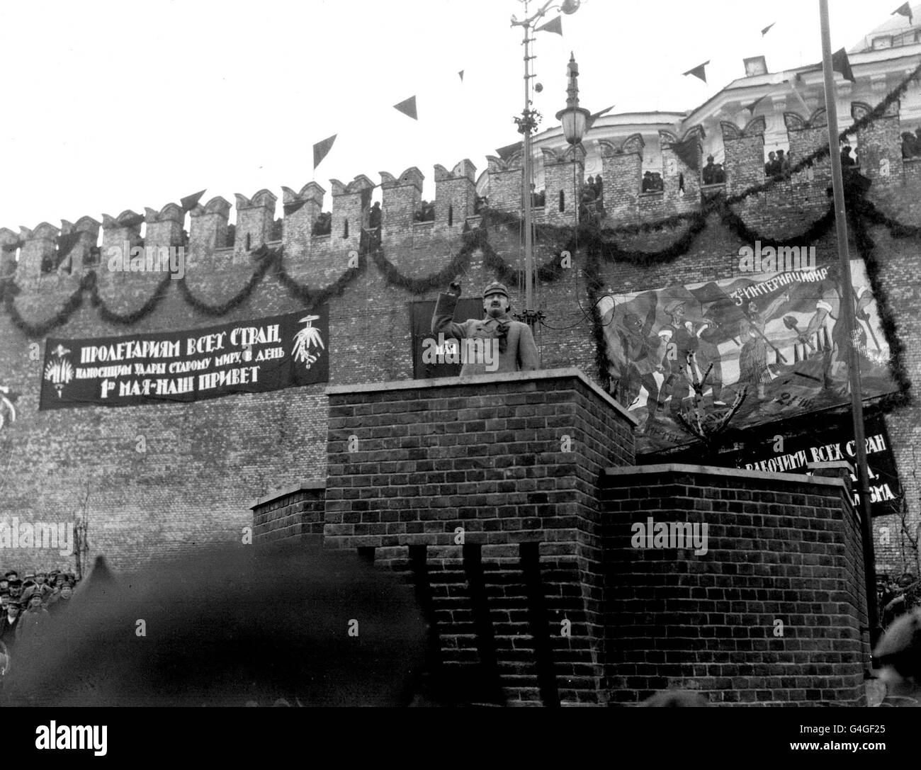 IL GIORNO DI MAGGIO A MOSCA È STATA SEGNALATA DA UNA PARATA DELLE TRUPPE SOVIETICHE IN PIAZZA ROSSA E DA UN DISCORSO DI LEON TROTSKY AL CREMLINO. QUI TROTSKY SI RIVOLGE ALLE TRUPPE ROSSE E AGLI SPETTATORI. LA GRANDE ISCRIZIONE A SINISTRA RECITA: 'IL PROLETARIATO DI TUTTI I PAESI ANCORA SOTTO IL DOMINIO DEL VECCHIO MONDO SI UNISCE A NOI SU QUESTO PUÒ PRIMA. I NOSTRI SALUTI'. Foto Stock
