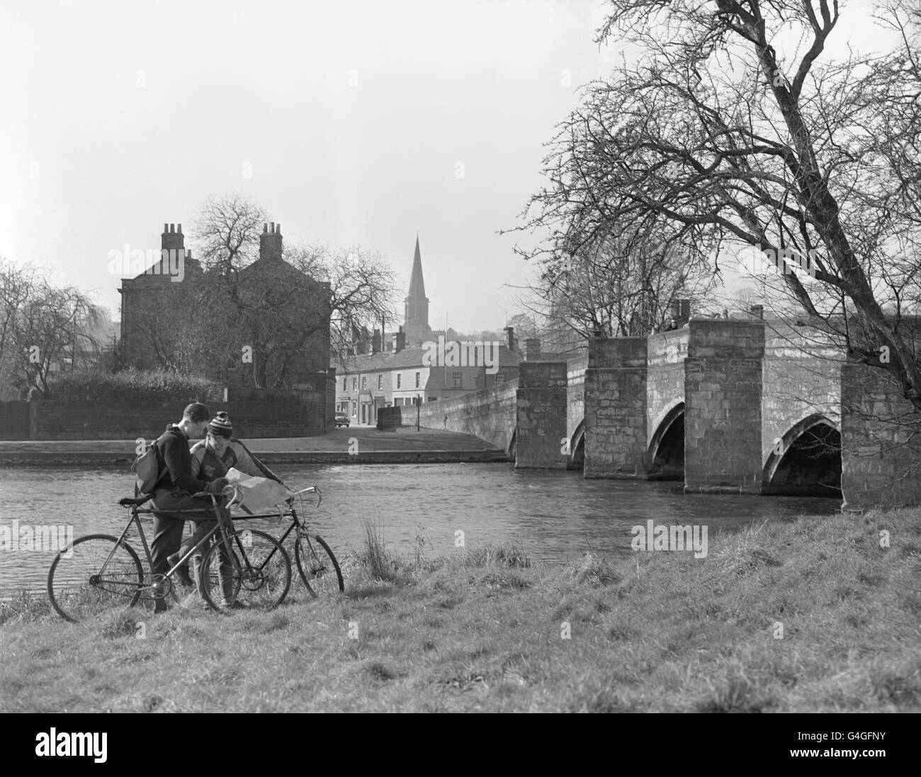 Il fiume Wye scorre sotto il ponte a Bakewell, Derbyshire. Il ponte gotico è uno dei più antichi della Gran Bretagna. La Chiesa dei Santi di Bakewell può essere vista in lontananza Foto Stock