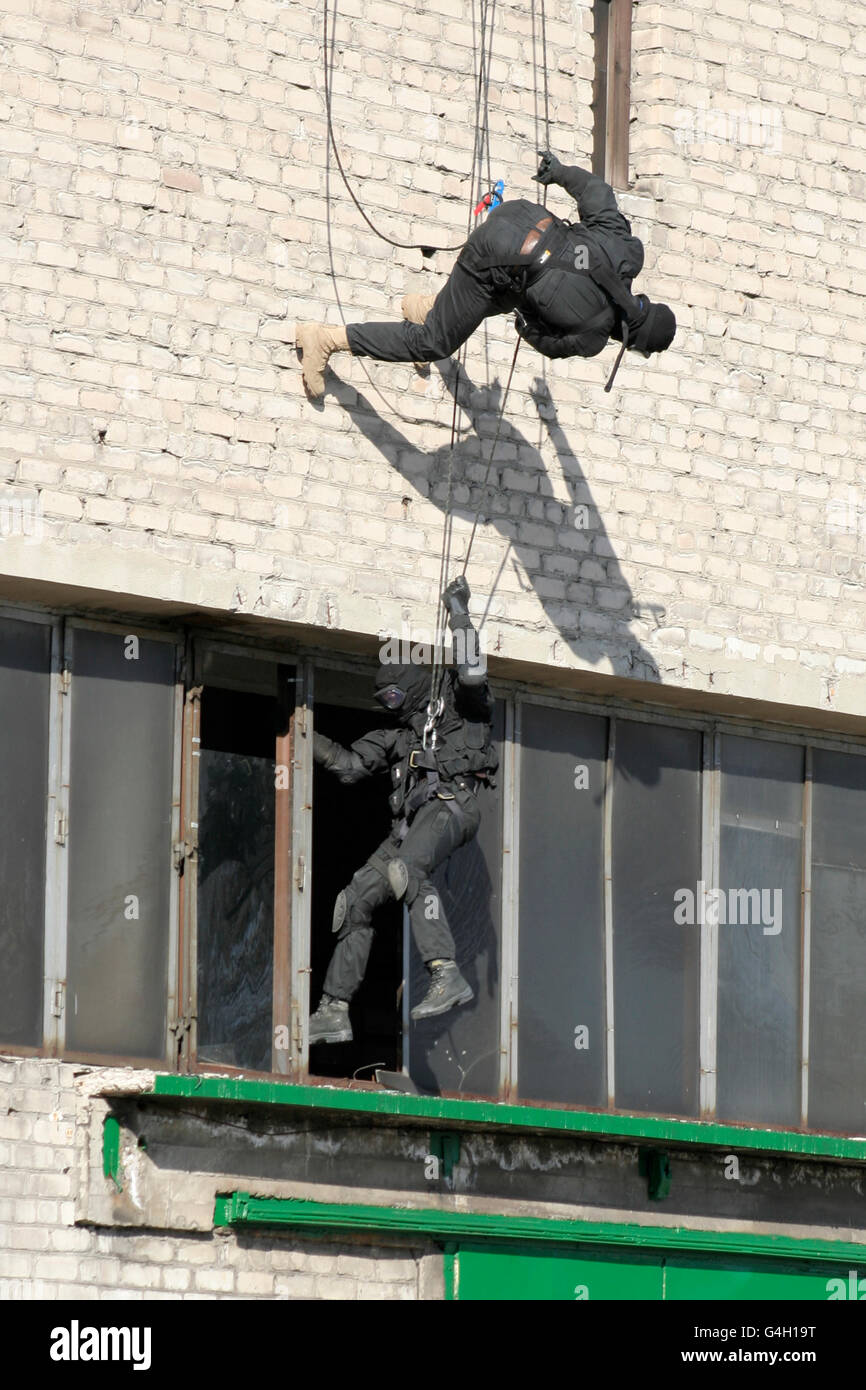 Suddivisione polizia anti-terrorismo durante un black tactical esercizi. Tecniche di corda. Situazione reale. Foto Stock