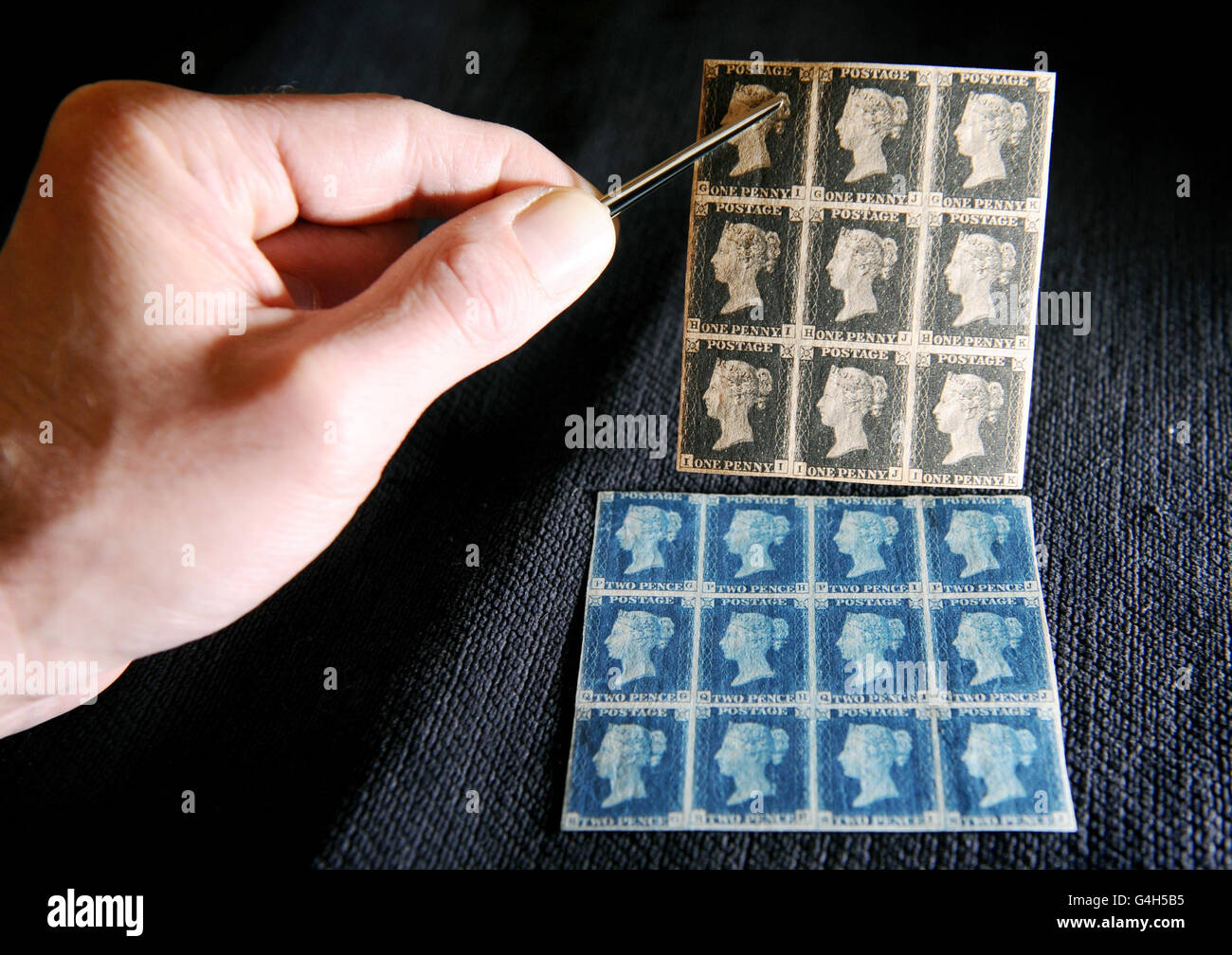 Un membro dello staff detiene un blocco di nove 1840 francobolli neri da 1 d, stimati tra il 150,000 e il 200,000, accanto ad un blocco di dodici 1840 francobolli 2d blu scuro, stimati tra il 80,000 e il 120,000, parte della Collezione filatelica di Lord Steinberg a Sotheby's, nel centro di Londra. Foto Stock