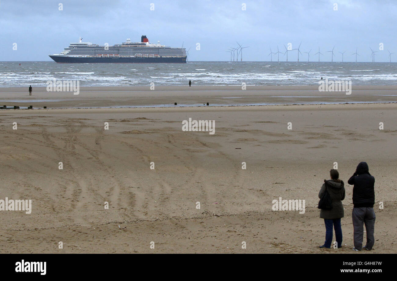 La nave passeggeri di Cunard, la regina Elisabetta, oltrepassa l'altro posto di Antony Gormley a Crosby Merseyside. La nave da crociera attracca a Liverpool come parte del Mersey River Festival 2011. Foto Stock