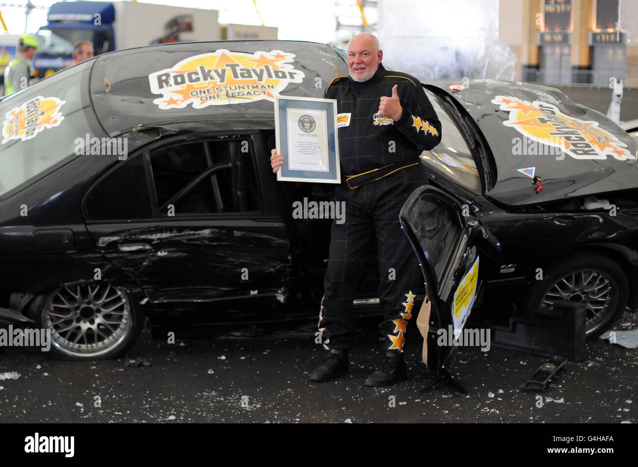Hollywood stuntman Rocky Taylor, 64, dopo aver infranta il Guinness World Record per la 'più grande struttura di vetro infrangibile abbattuto da un'auto' alla O2 Arena, a Greenwich, Londra. Foto Stock