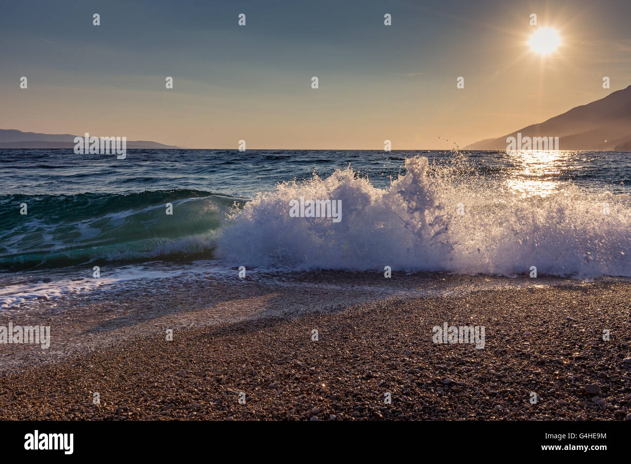 Retroilluminazione al tramonto. Onda del mare Adriatico. Spiaggia di Zlatni Rat. Bol, isola di Brac, Croazia. Europa. Foto Stock