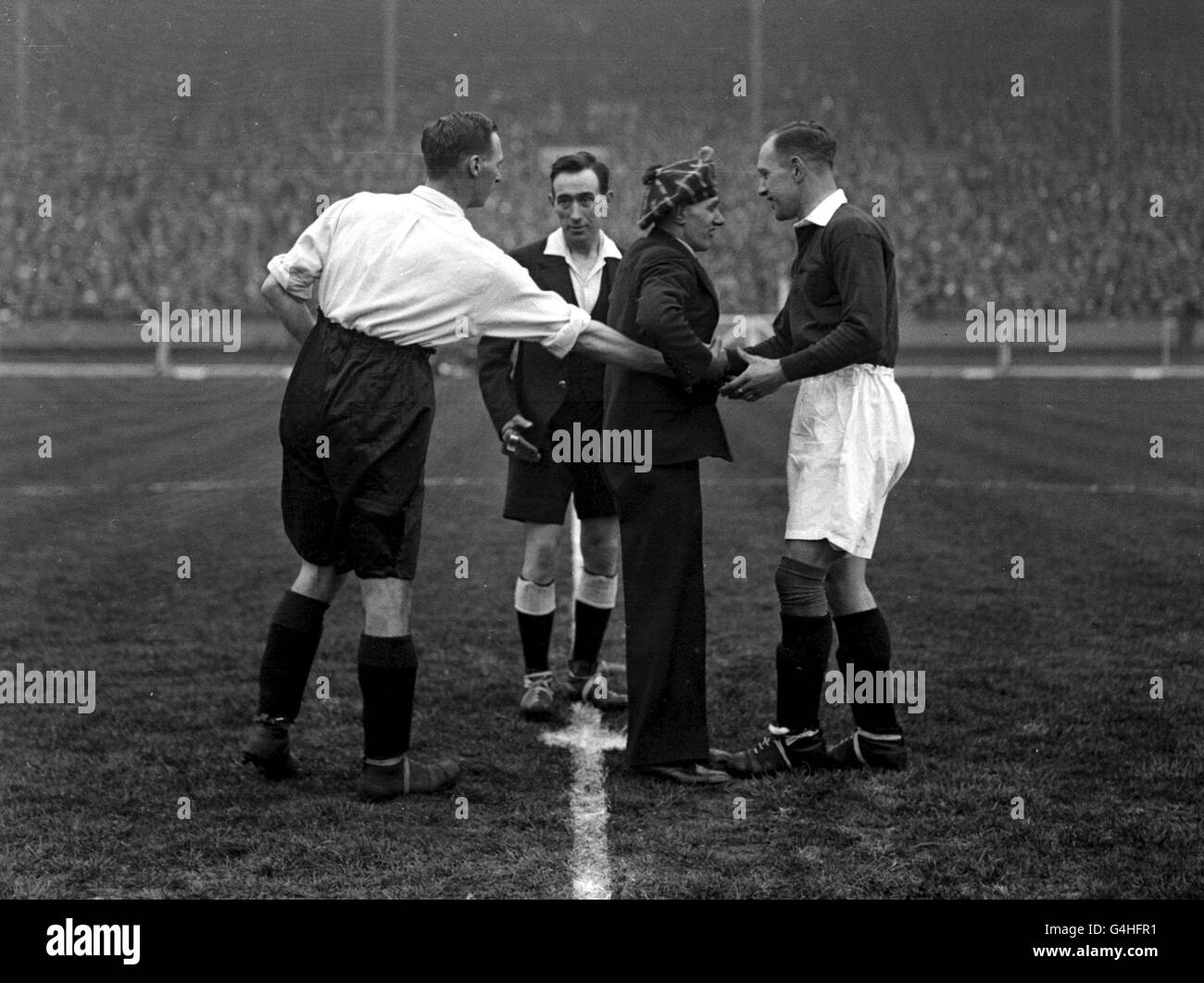 PA NEWS PHOTO 5/4/30 DAVID JACK (A SINISTRA) CAPITANO D'INGHILTERRA SCUOTE LE MANI CON D. MEIKLEJOHN (CAPITANO DELLA SCOZIA) PRIMA DEL CALCIO D'INIZIO TRA L'INGHILTERRA E LA SCOZIA A WEMBLEY, LONDRA. IL CENTRO È WILLIAMS MCLEAN, ARBITRO DI BELFAST Foto Stock