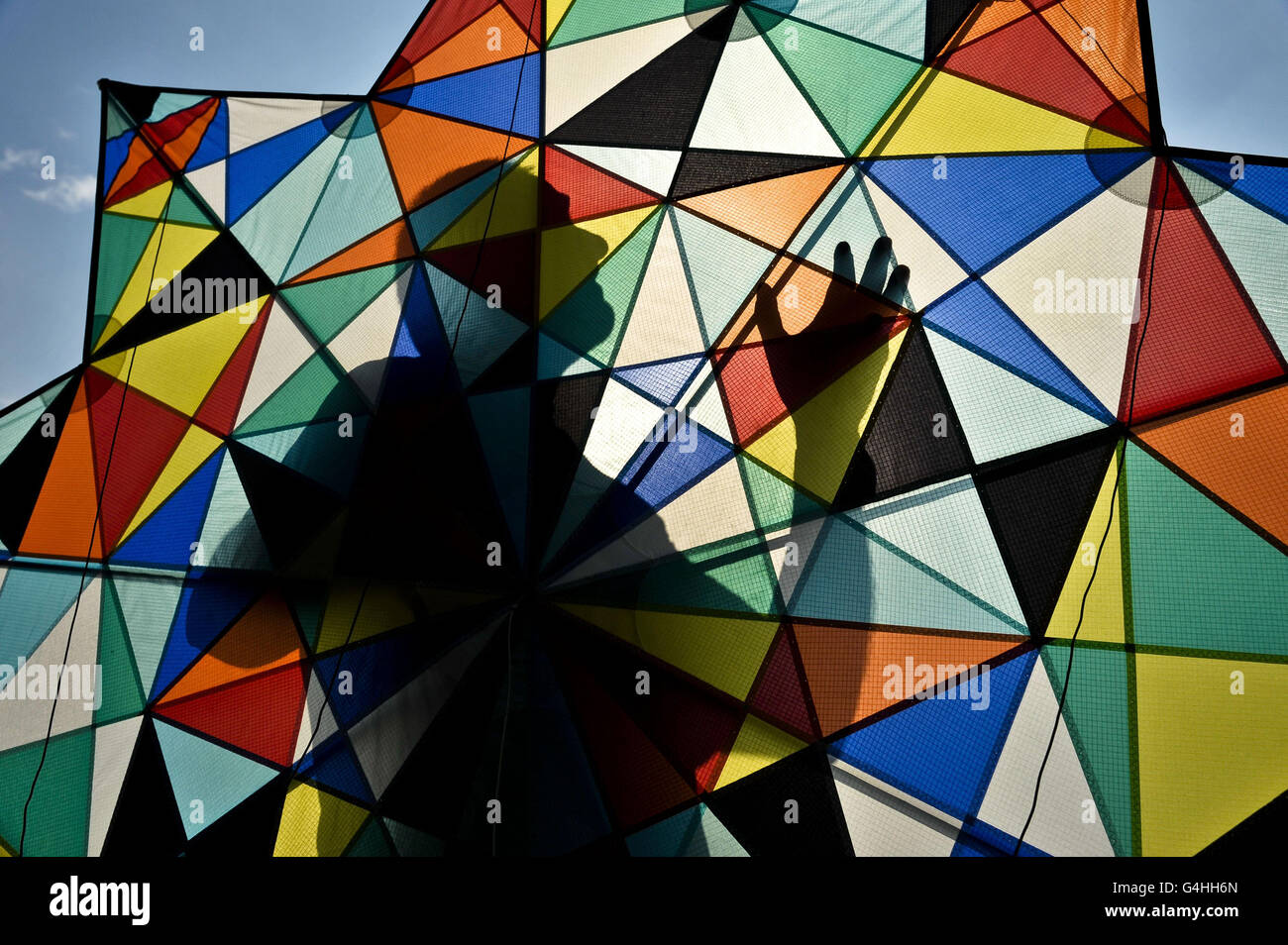 Un kite flier è silhoueted mentre cammina il suo aquilone fuori per il decollo su Durdham Downs a Bristol mentre la città si prepara ad ospitare l'International Kite Festival. Foto Stock