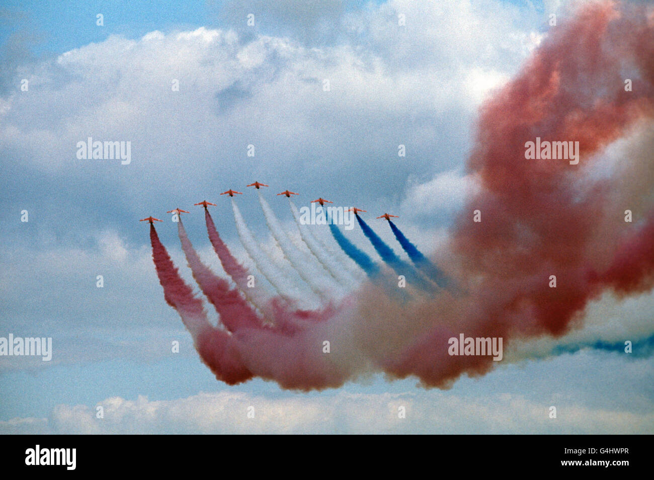 Percorsi di fumo rosso, bianco e blu della squadra di aerobica Red Arrows in prossimità della mostra di volo, alla Royal Review della Royal Air Force, alla RAF Finningley, durante il tour Silver Jubilee della Gran Bretagna della Regina Elisabetta II Foto Stock