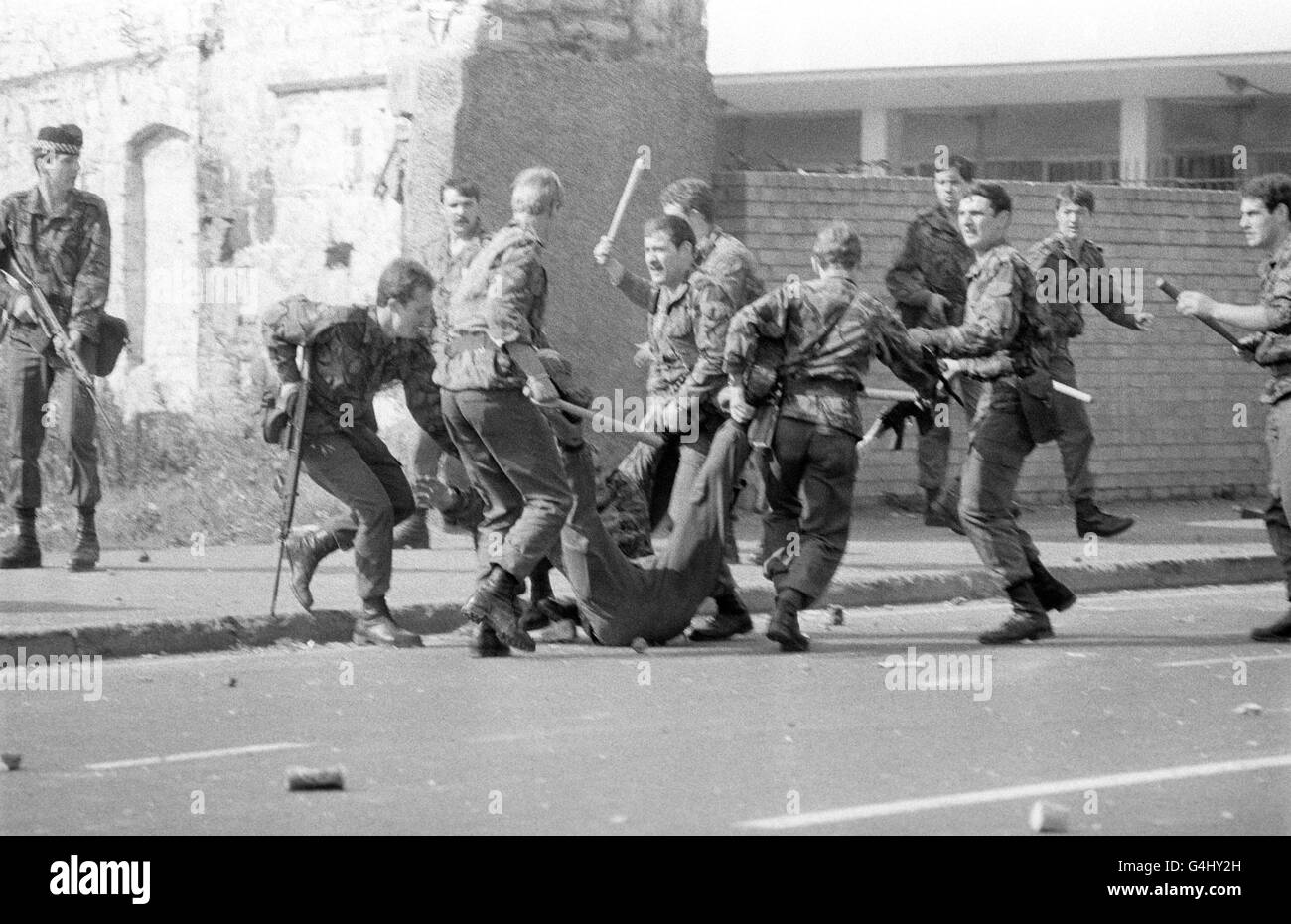 Un soldato ferito viene trascinato via dai suoi compagni durante una sommossa nella Falls Road, Belfast, il primo giorno della visita Silver Jubilee della Regina Elisabetta II in Irlanda del Nord. Foto Stock