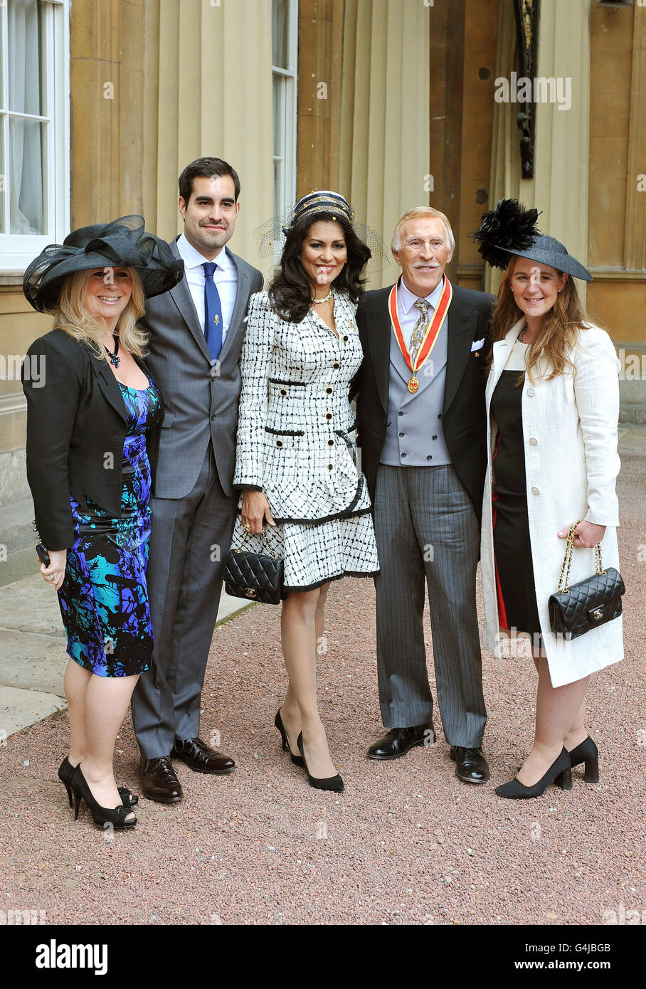 Sir Bruce Forsyth si trova con sua moglie Wilnelia, le sue figlie Laura (a sinistra) e Charlotte, e il figlio Jonathan, dopo essere stato nominato cavaliere dalla Regina Elisabetta II durante una cerimonia di investitura a Buckingham Palace, Londra. Foto Stock