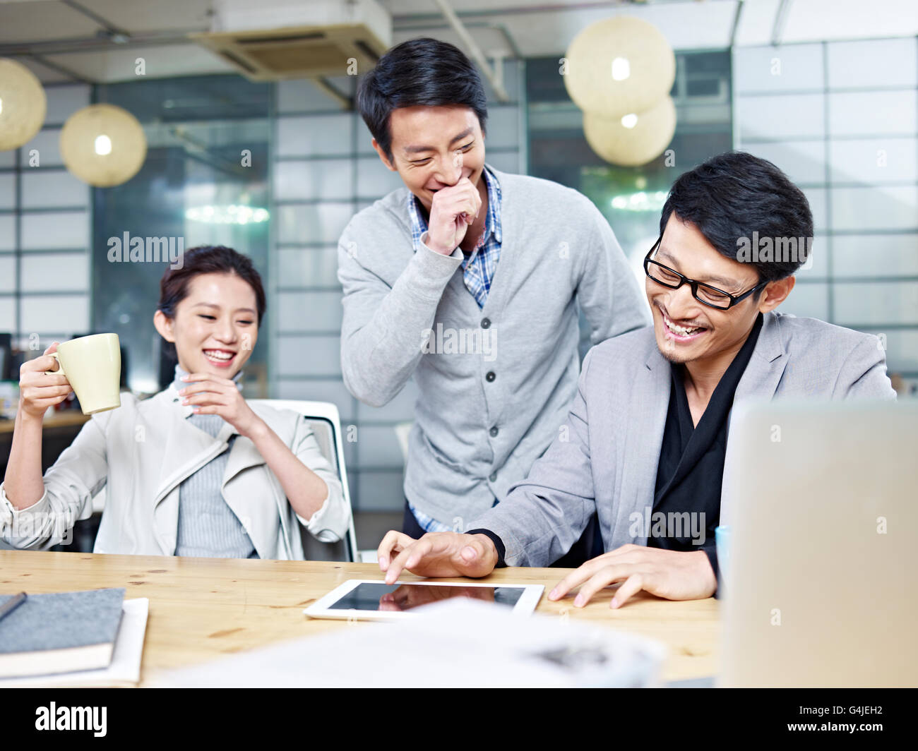Un team di giovani imprenditori asiatici divertirsi mentre si lavora in ufficio. Foto Stock