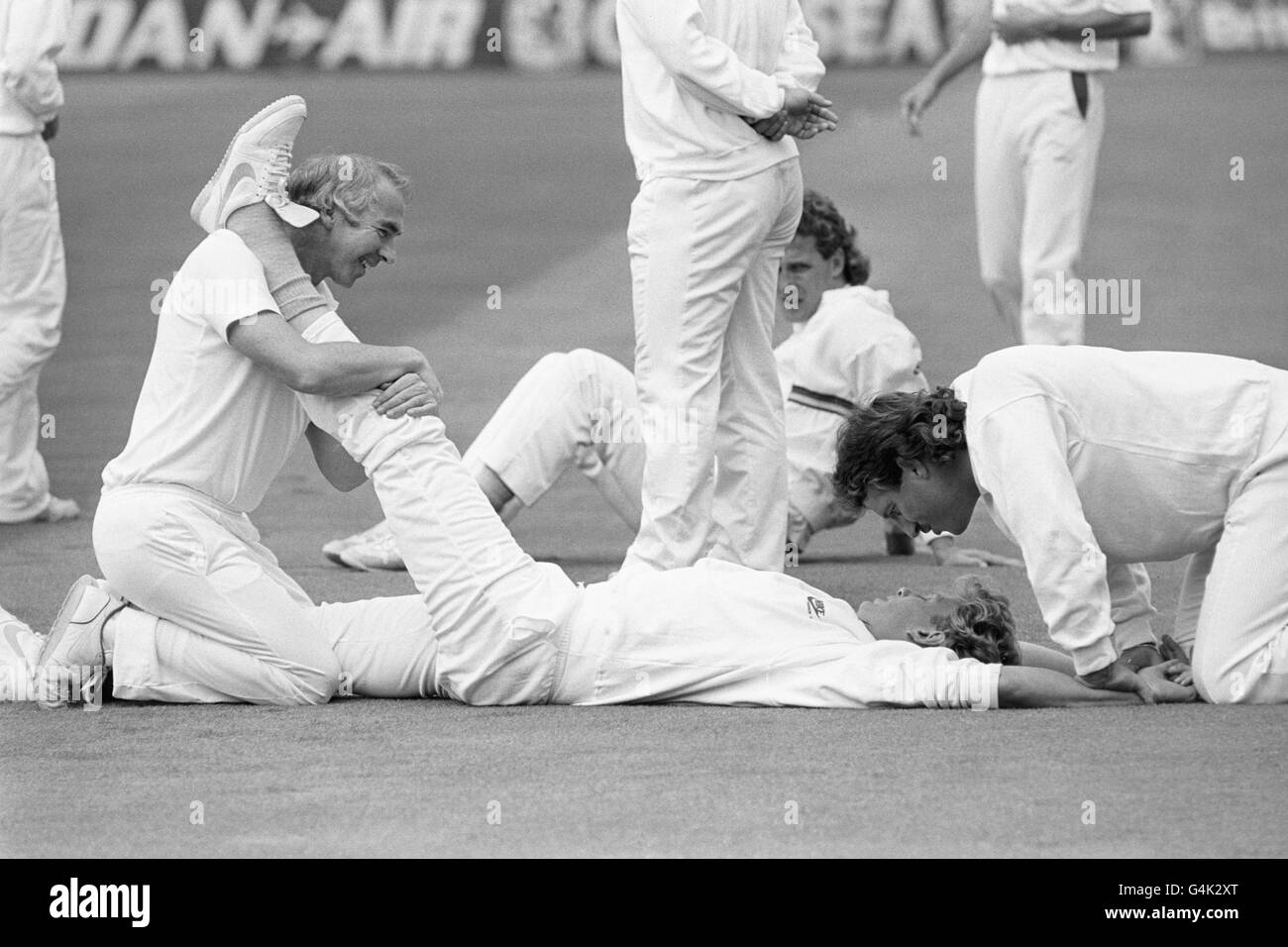 Inghilterra tutto-rounder Ian Botham, a destra, offre il compagno di squadra Graham Dilley alcune parole di incoraggiamento come il veloce bowler del Worcestershire ha le sue gambe stirate dal phyio Laurie Brown all'ovale. Foto Stock