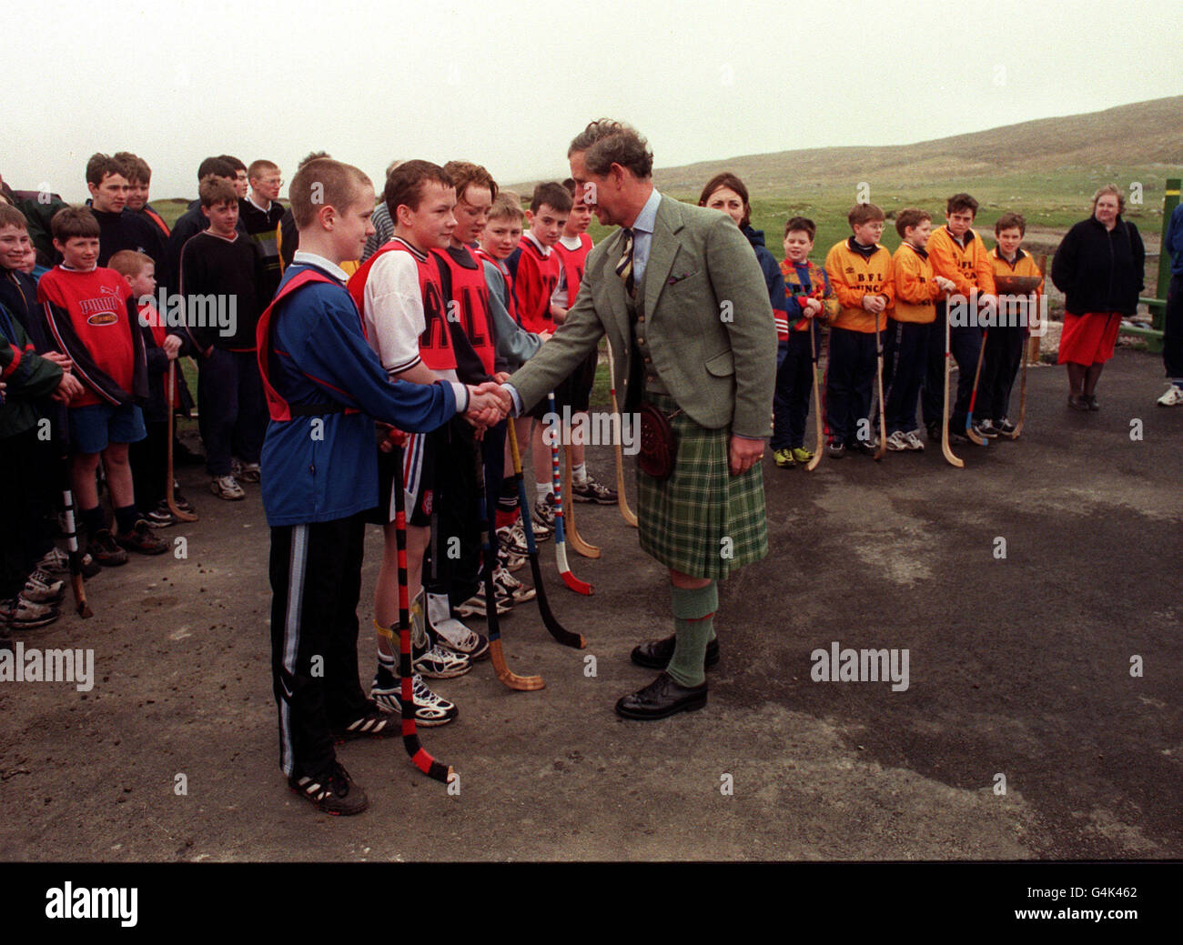 Il Principe di Galles scrolla le mani con i giovani giocatori di Shinty dopo averli presentati con un premio sull'Isola di Berneray. Era sull'isola per aprire la strada che la collega con il suo vicino meridionale North Uist nelle Ebridi esterne, in Scozia. Foto Stock