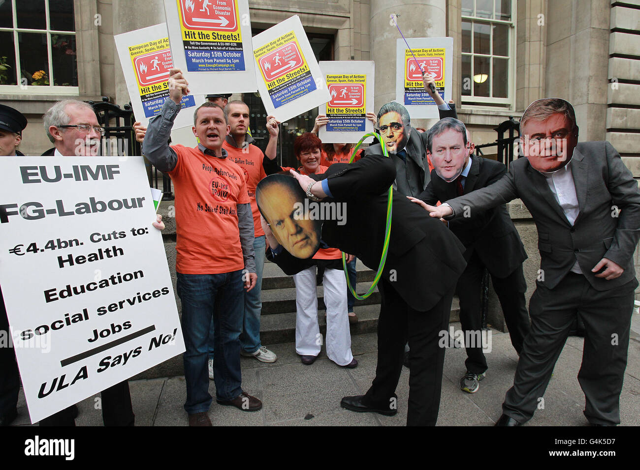 United Left Alliance TD Richard Boyd Barrett (seconda a sinistra) Insieme ad altri membri dell'ULA, stage una fotocall che raffigura il ministro delle Finanze Micheal Bruton che viene frustato e spinto attraverso un cerchio da Ajai Chopra del FMI, Taoiseach Enda Kenny e Tanaiste Eamon Gilmore fuori dagli uffici del Dipartimento delle Finanze in via Merrion, a Dublino, Come parte della loro protesta contro il salvataggio del FMI. Foto Stock