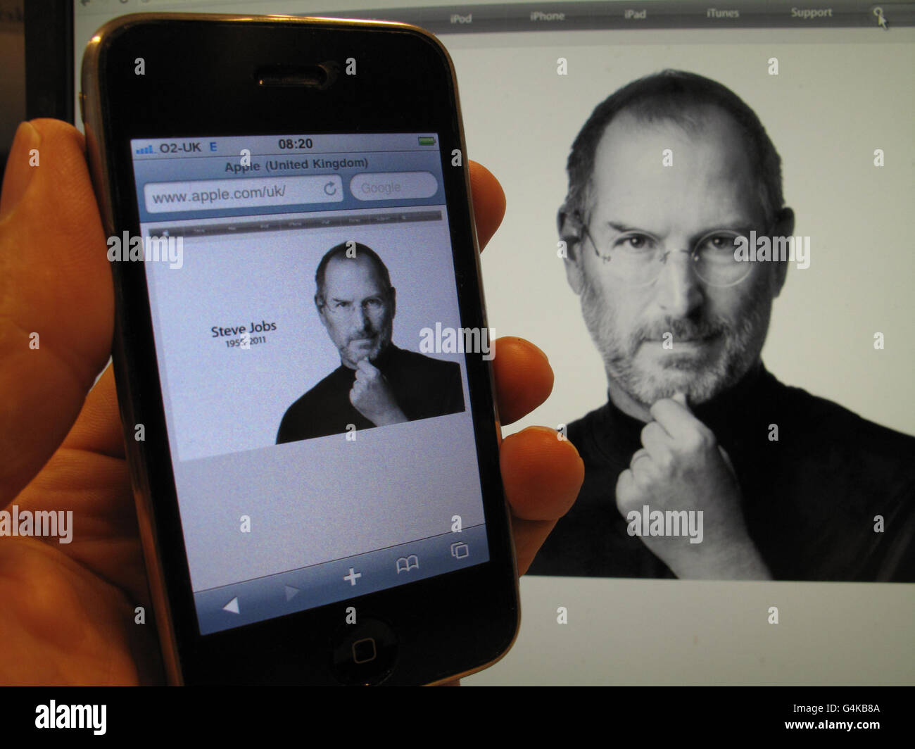 Un iPhone e un computer desktop mostrano il tributo del sito web Apple a Steve Jobs, che è morto di 56 anni. Foto Stock