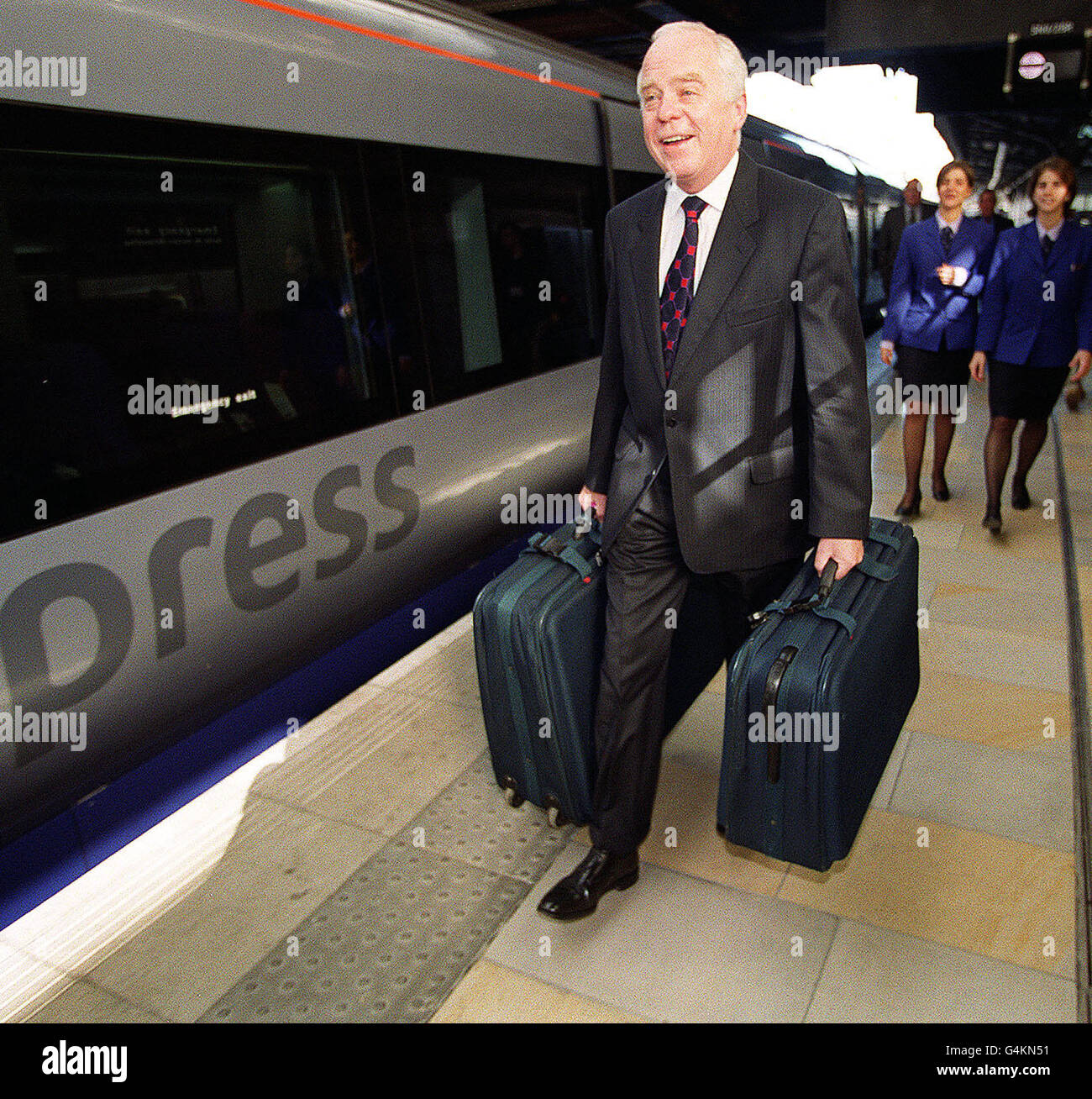 Sir John Egan arriva alla stazione di Paddington, durante le prove per l'apertura del più grande terminal remoto del mondo, il nuovo check-in BAA Heathrow Express, che prevede 27 banchi di check-in delle compagnie aeree serviti da tutte le principali compagnie aeree. * sfondo presenta due membri del personale espresso di Heathrow in uniforme, Caterine Well (L) e Debbie Syme (R). Il check-in è aperto dal 23 1999 giugno Foto Stock