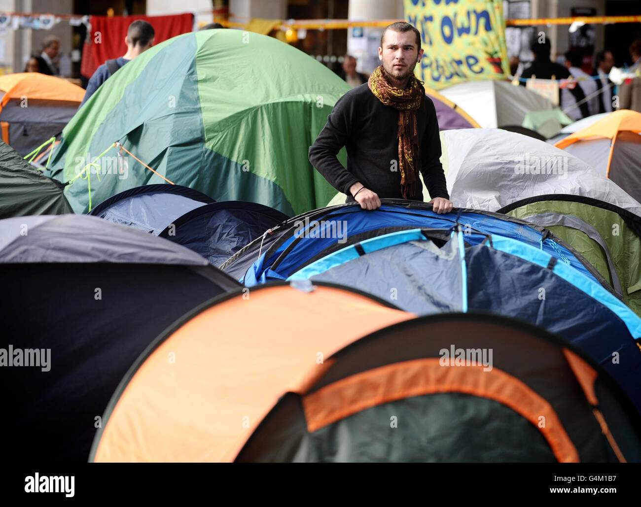 Un protestore erige una tenda nel luogo della manifestazione Occupy the London Stock Exchange, fuori dalla cattedrale di St Paul's, nel centro di Londra. Foto Stock