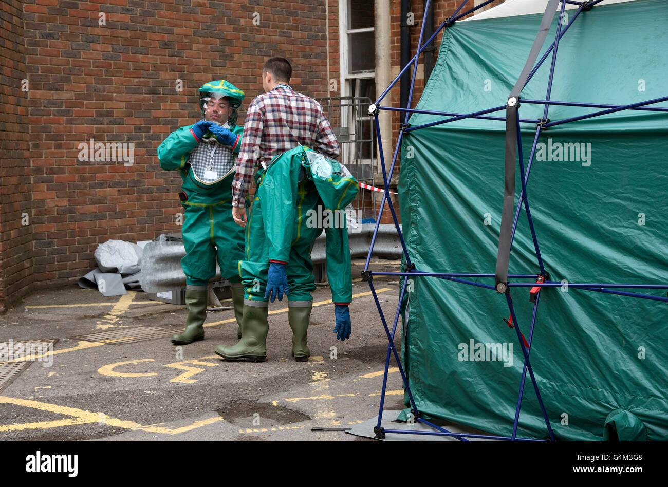 Gli uomini la rimozione di loro tute di decontaminazione che è passata attraverso una tenda di decontaminazione Foto Stock