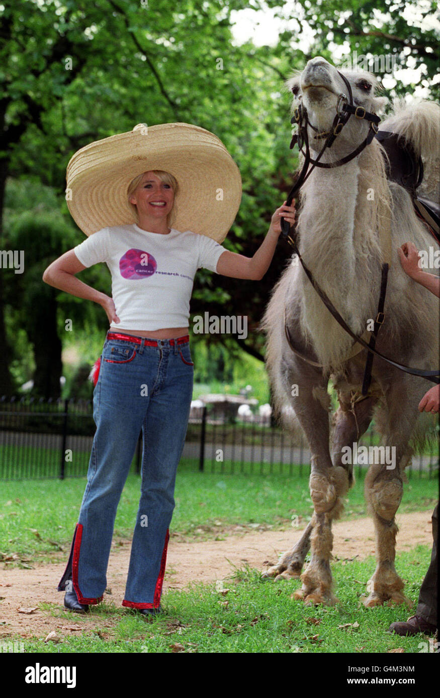 L'attrice Michelle Collins si pone con un cammello Bactrio allo Zoo di Londra, per lanciare l'appello straniero della Campagna di Ricerca sul cancro. La campagna sta esortando il pubblico a sostenere l'appello che trasforma le monete rimanenti in sterline per trovare cure contro il cancro. Foto Stock